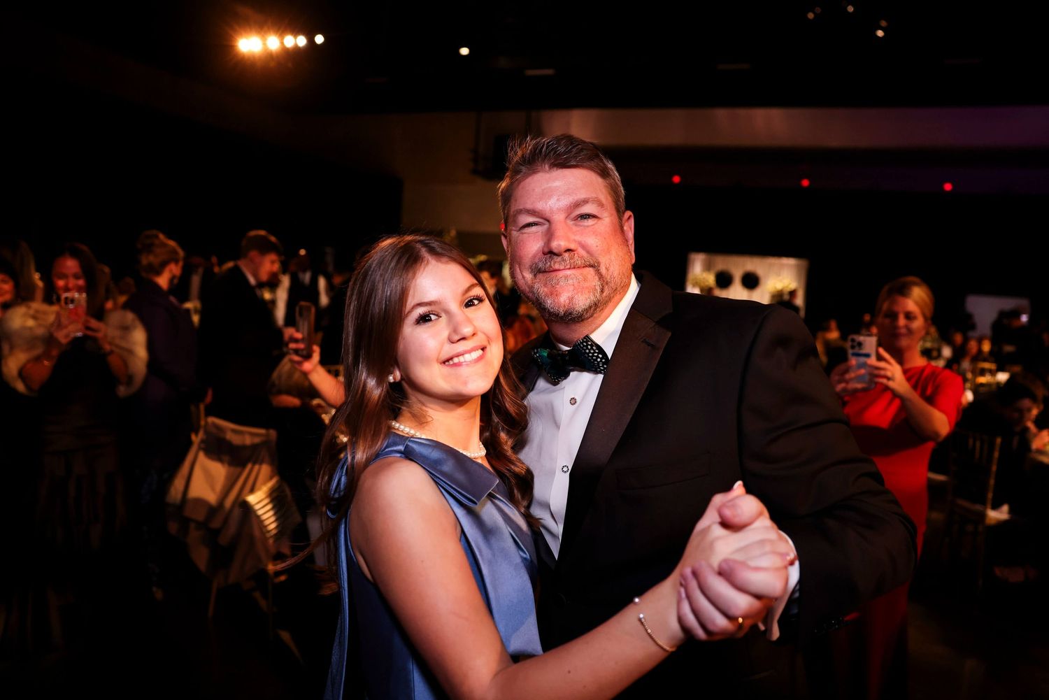Couples dancing together at a dimly lit wedding reception on a crowded dance floor.