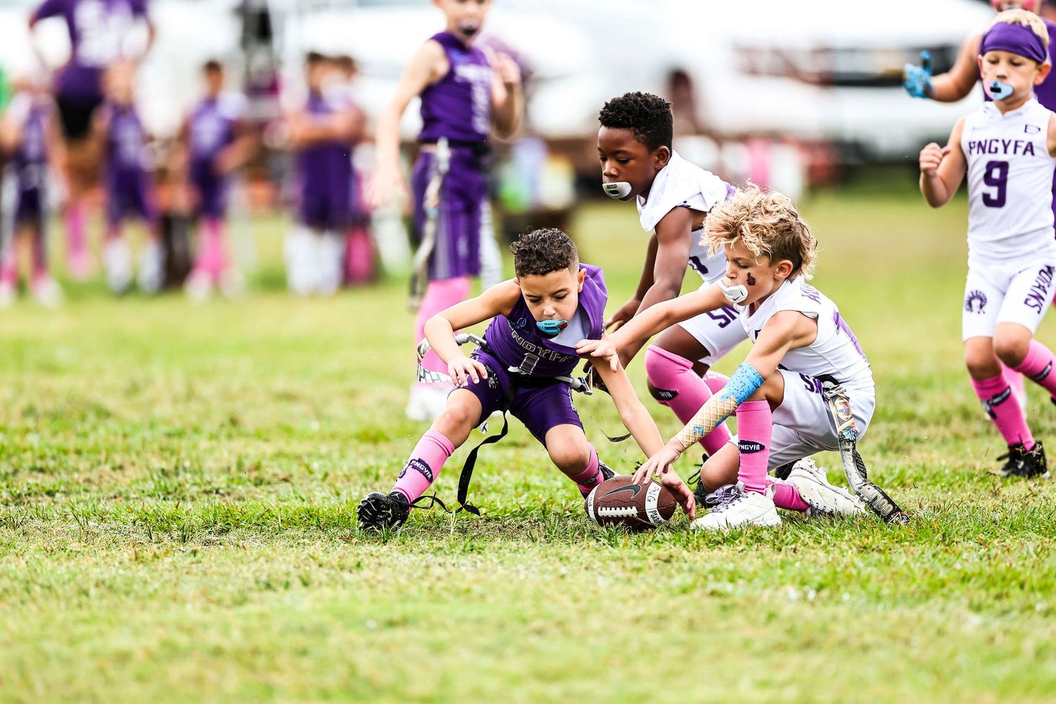 Youth sports players sit together on grass field during break.