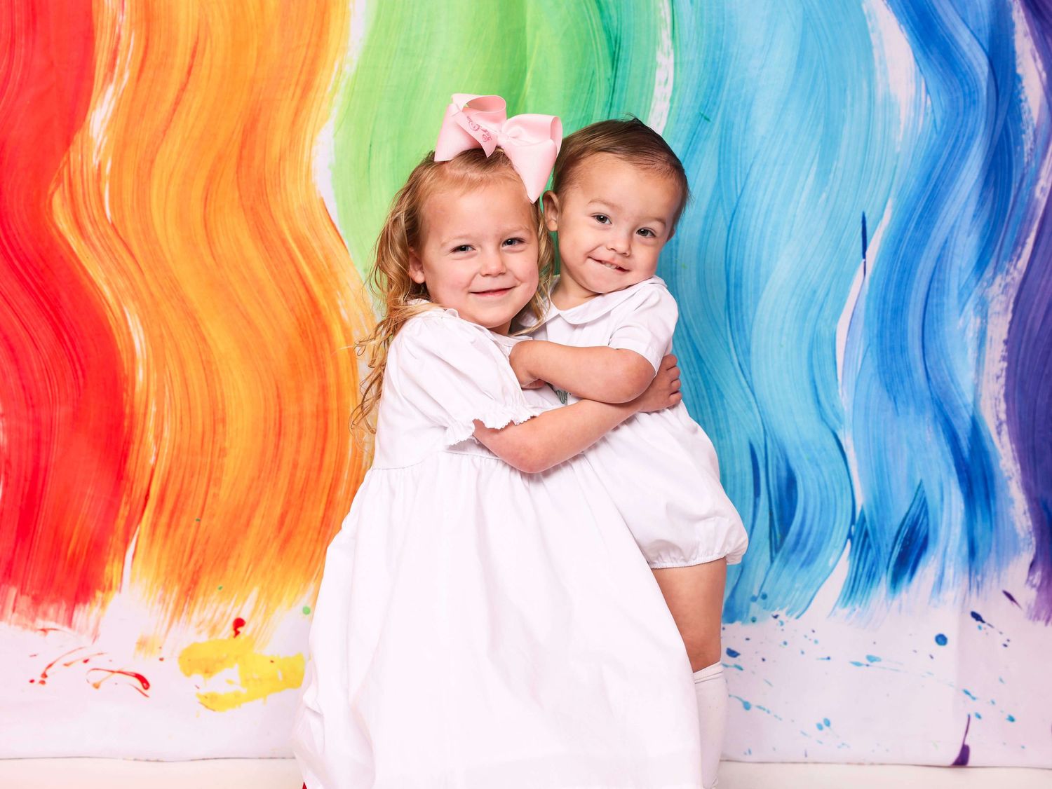 Colorful paint splatter background with vibrant red, green, and blue watercolor streaks creating a rainbow effect.