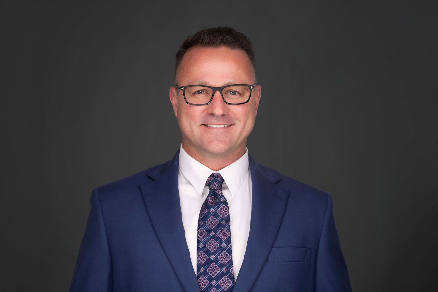 Business professionals in suits and ties photographed against dark background.