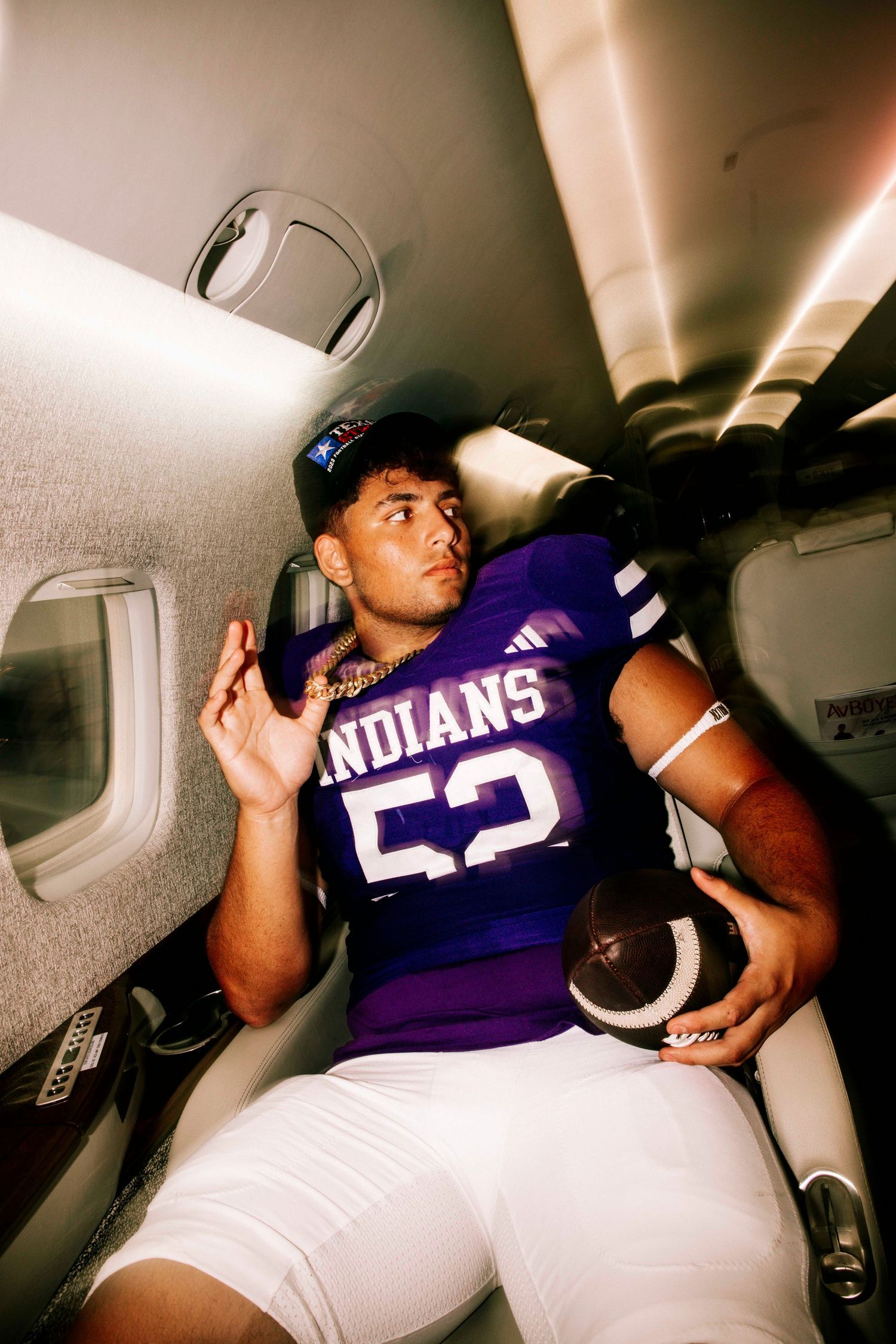 Football players in purple Indians jerseys lounging in aircraft cabin.