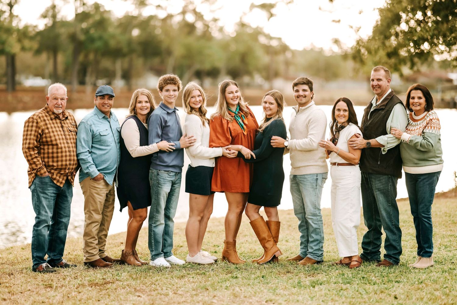 Large family group sitting together outdoors for a casual portrait session at sunset.