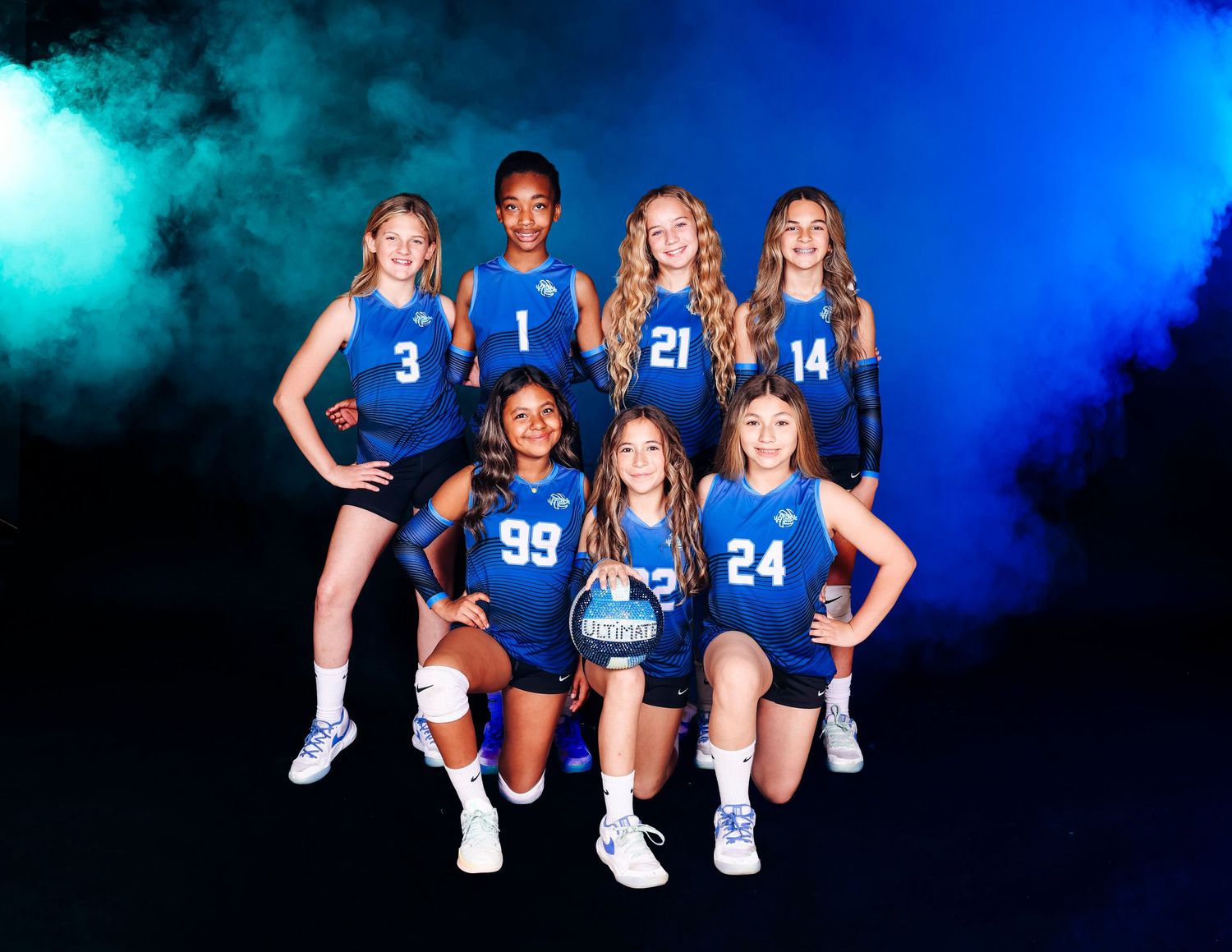 Volleyball team in blue uniforms poses together with dramatic lighting effects.