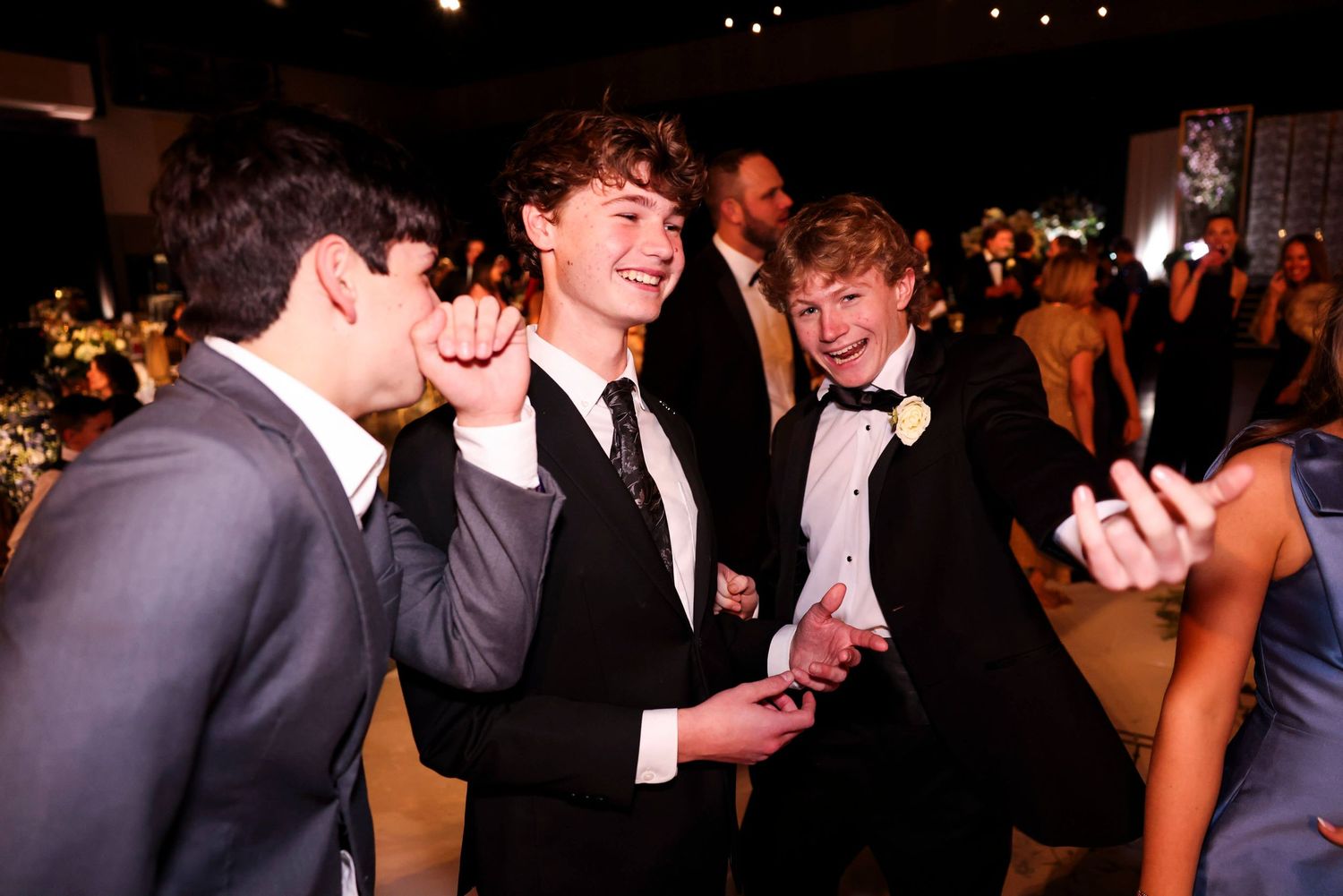 People dancing and socializing at a formal event with dark lighting and festive atmosphere.
