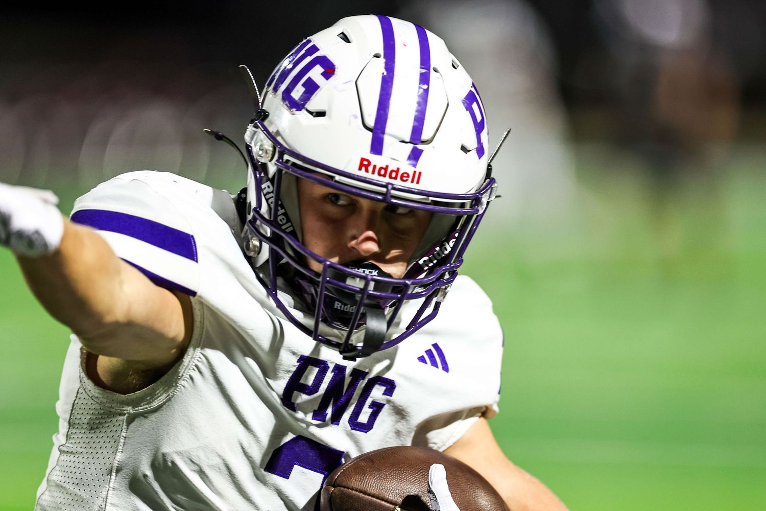 Football players in purple and white uniforms running plays during a game.