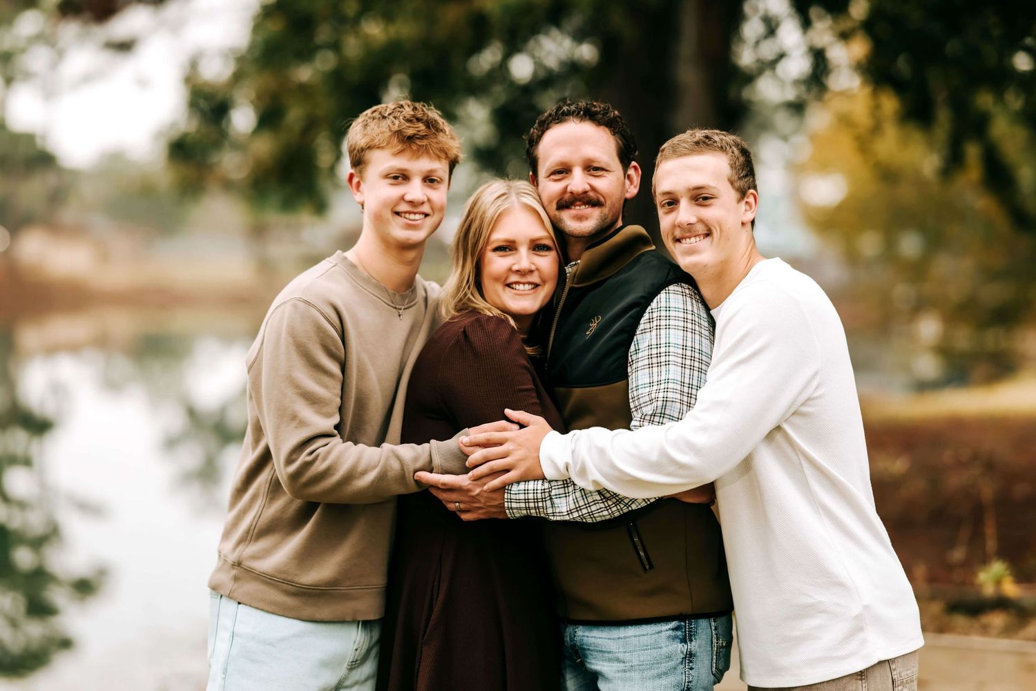 Candid family portrait showing playful interactions and laughter in a park setting.