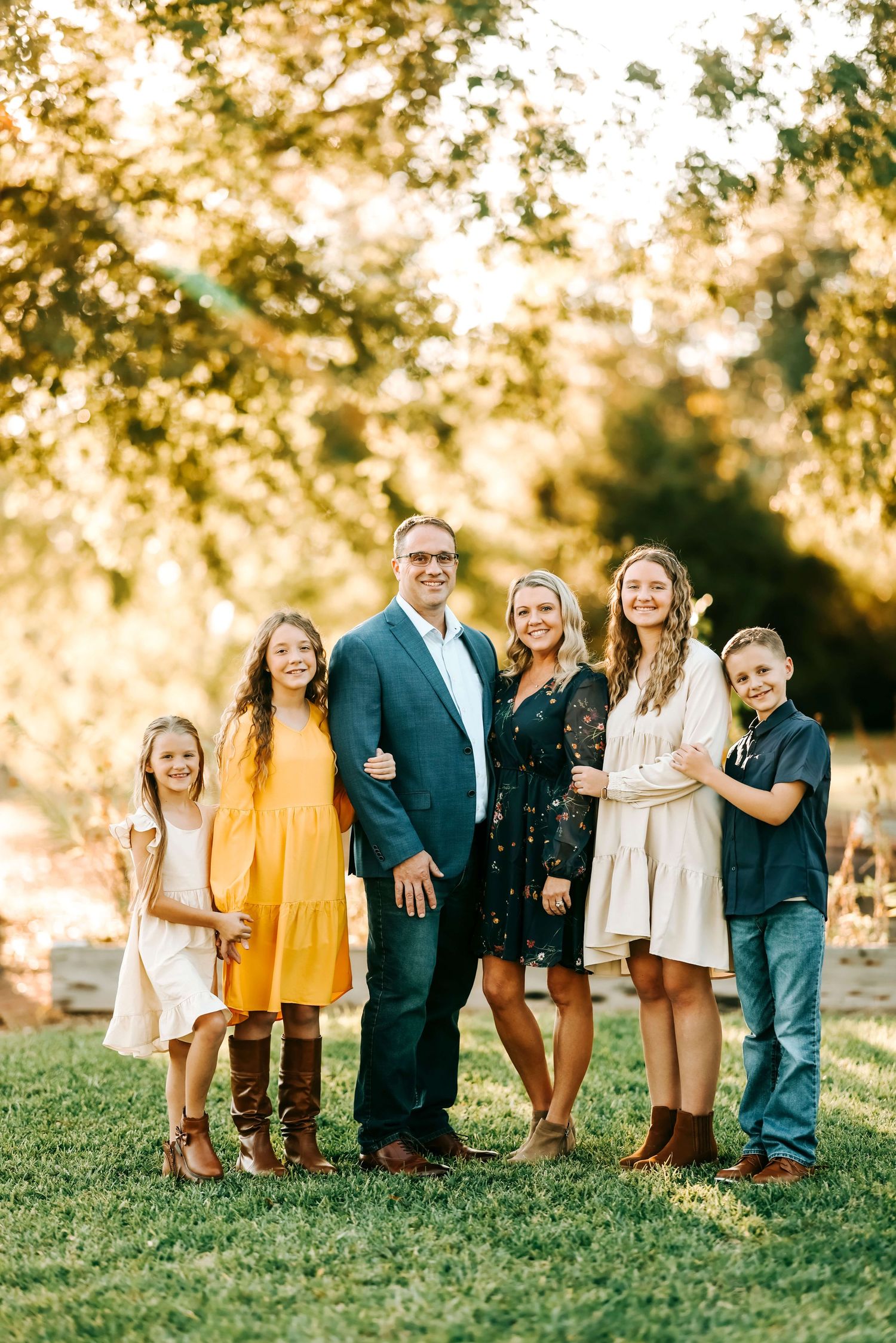 A group poses together on a grassy hill during golden hour.
