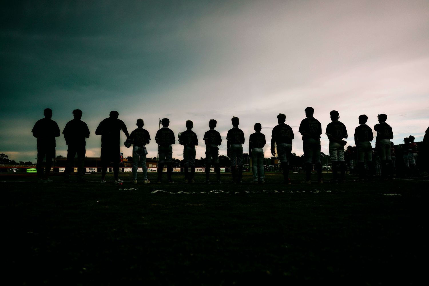 Silhouettes of people standing in a row against a dramatic sunset sky.