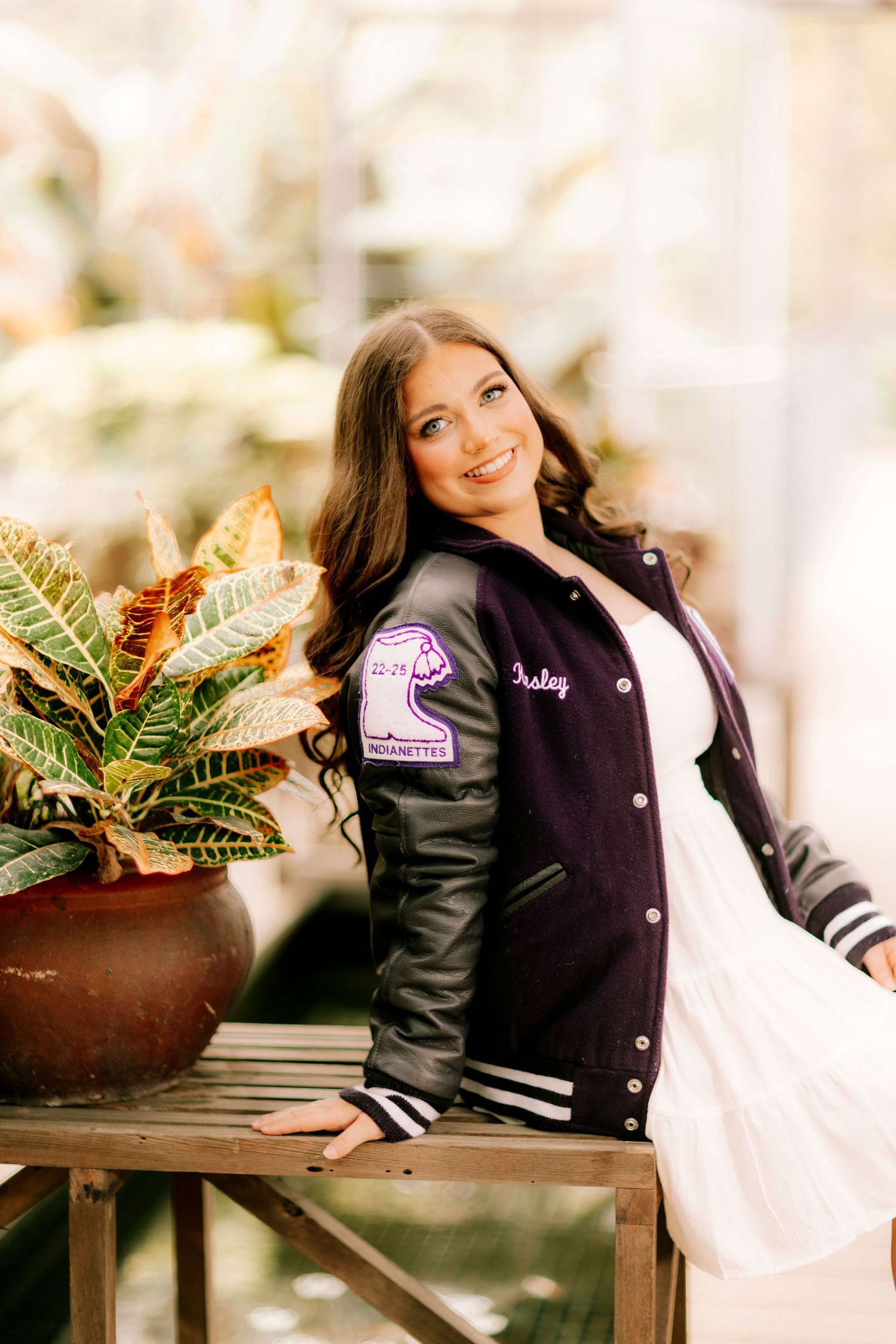 A varsity letterman jacket styled photo shoot with plants and decor in the background.