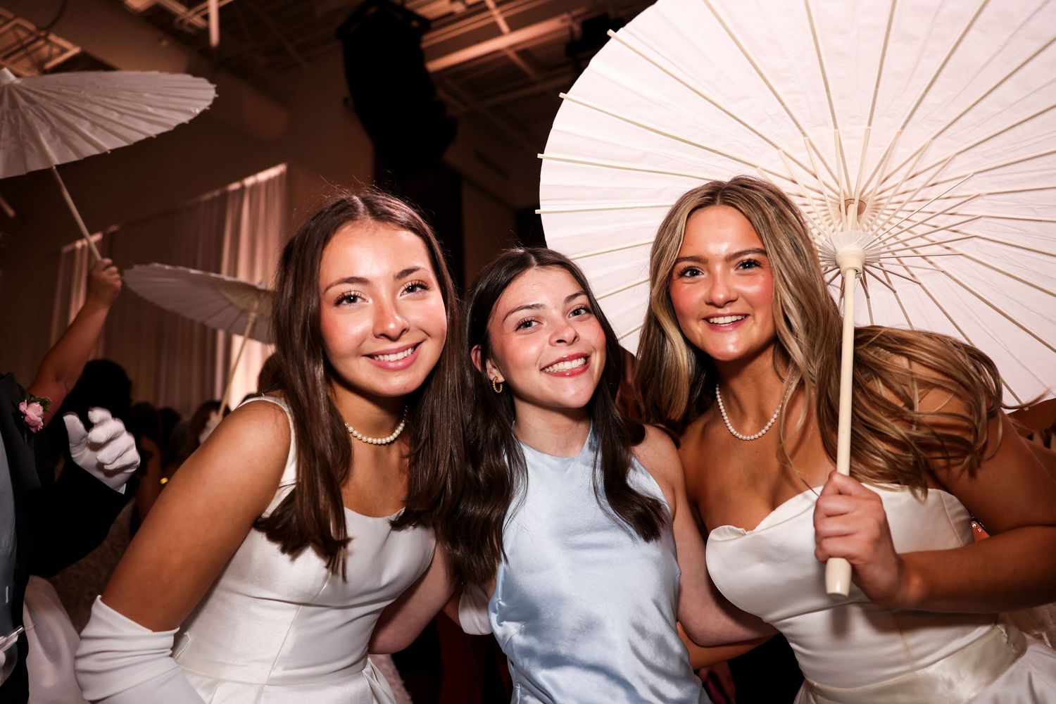 A group poses with white paper parasols at a party or celebration event.