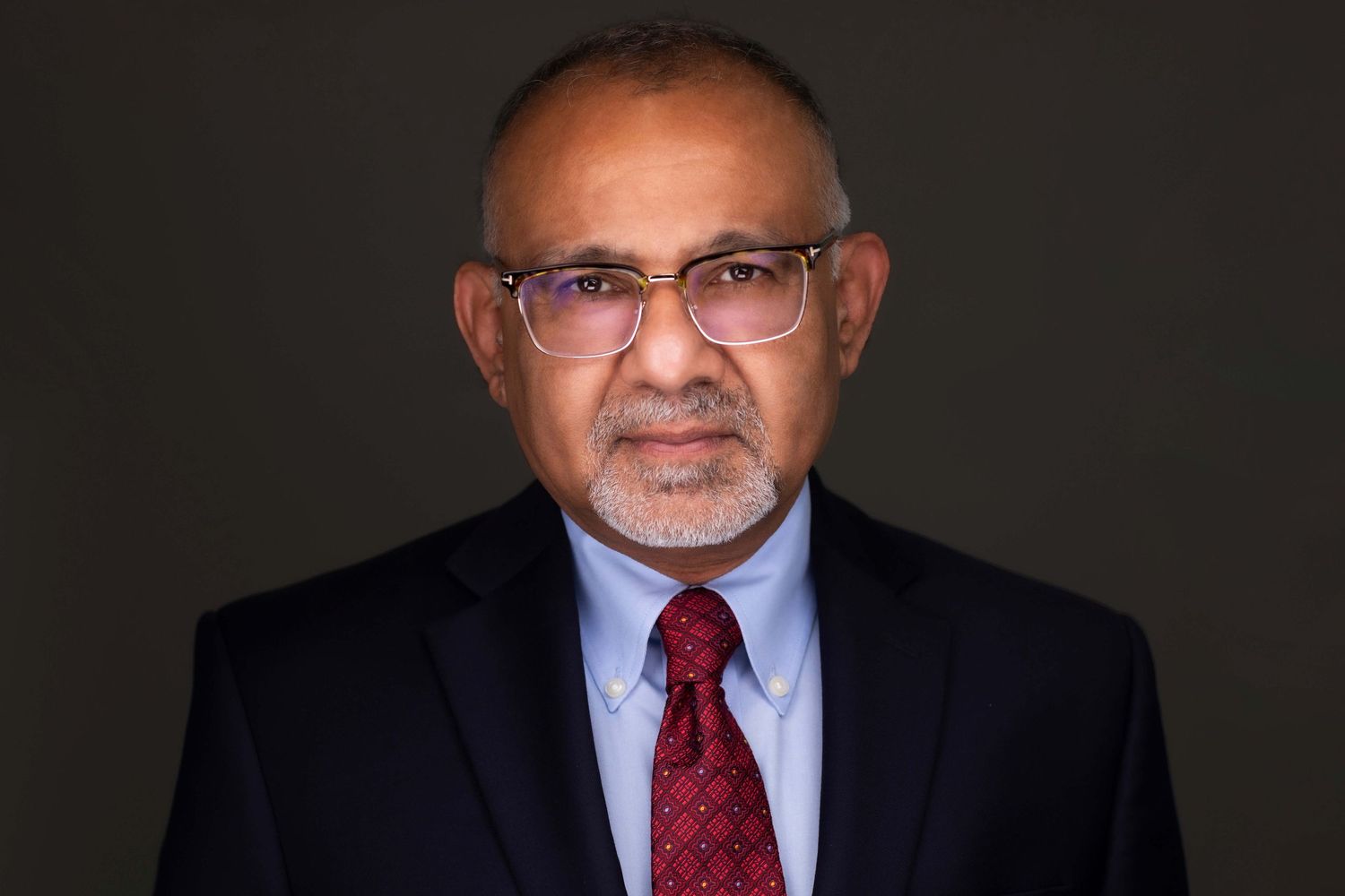 Professional headshots of executives in business attire against dark studio backdrop.