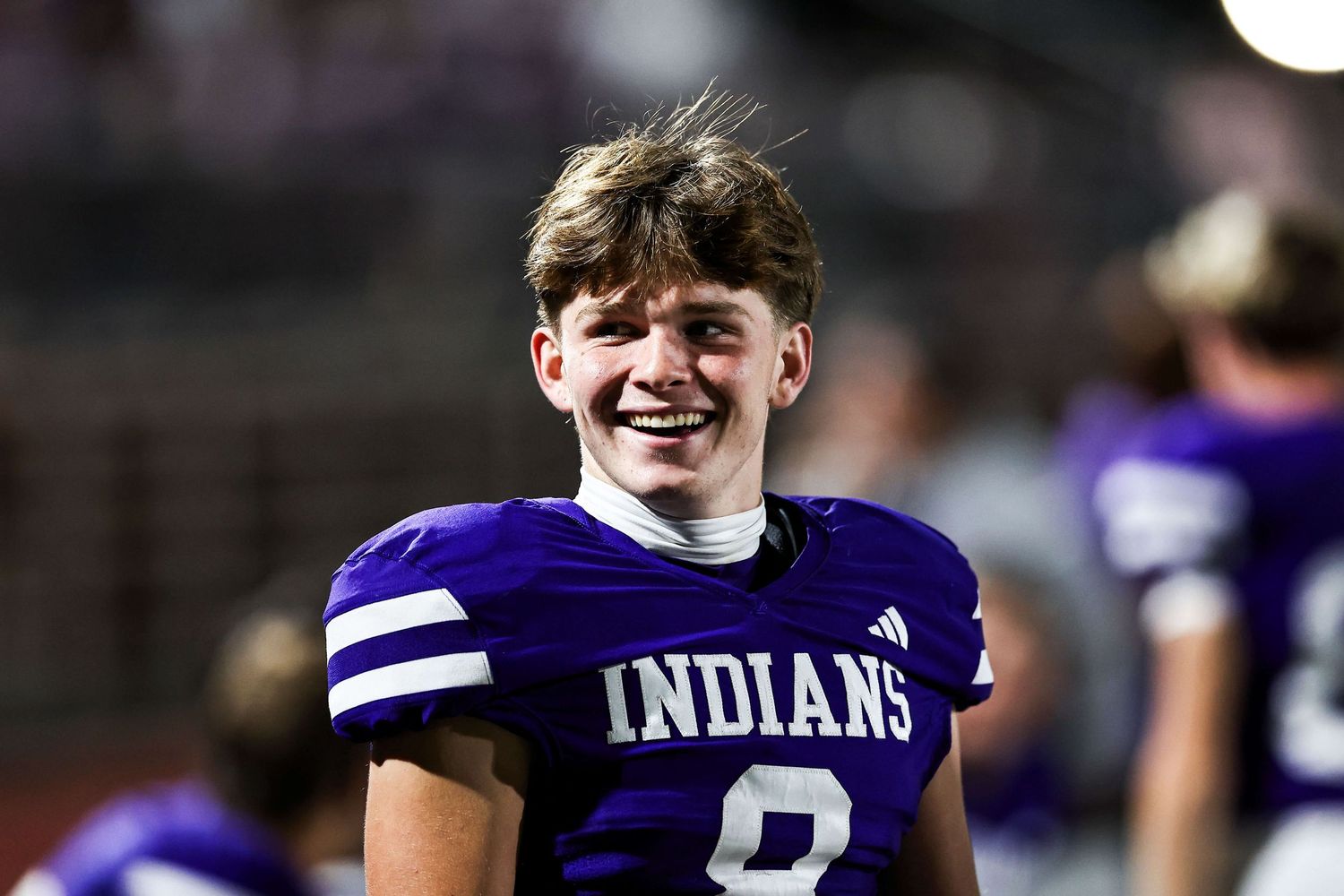 Football players in purple and white uniforms celebrating on the field.