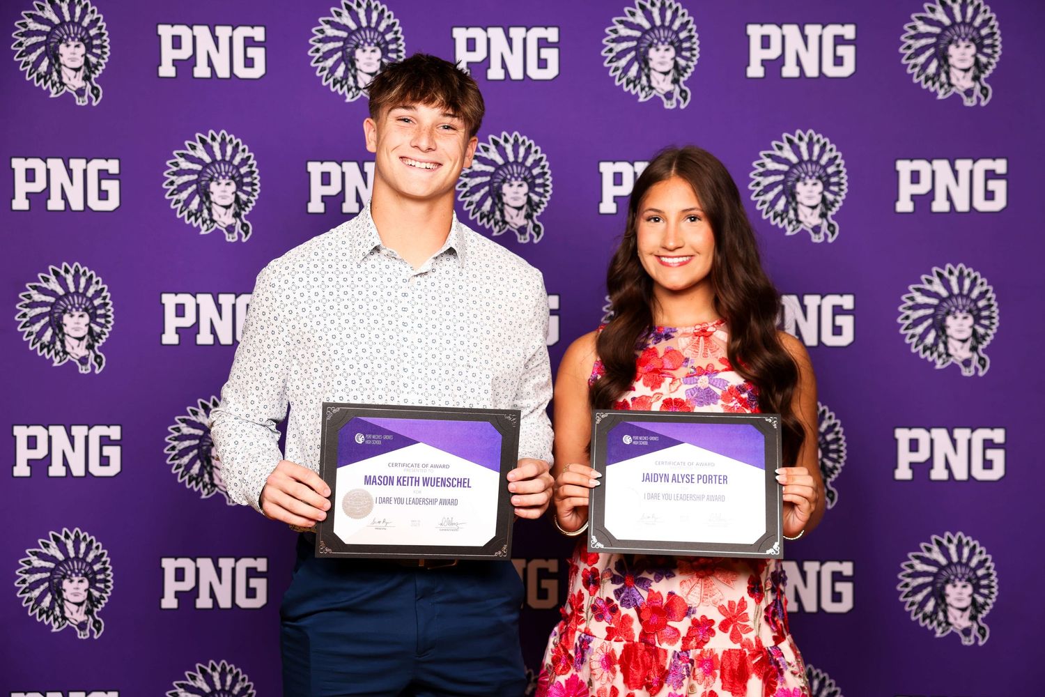Students pose with certificates against a purple backdrop with repeating PNG logo pattern.