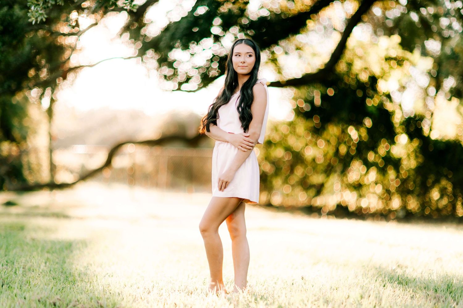 A sunny outdoor portrait session in a grassy field with natural lighting.