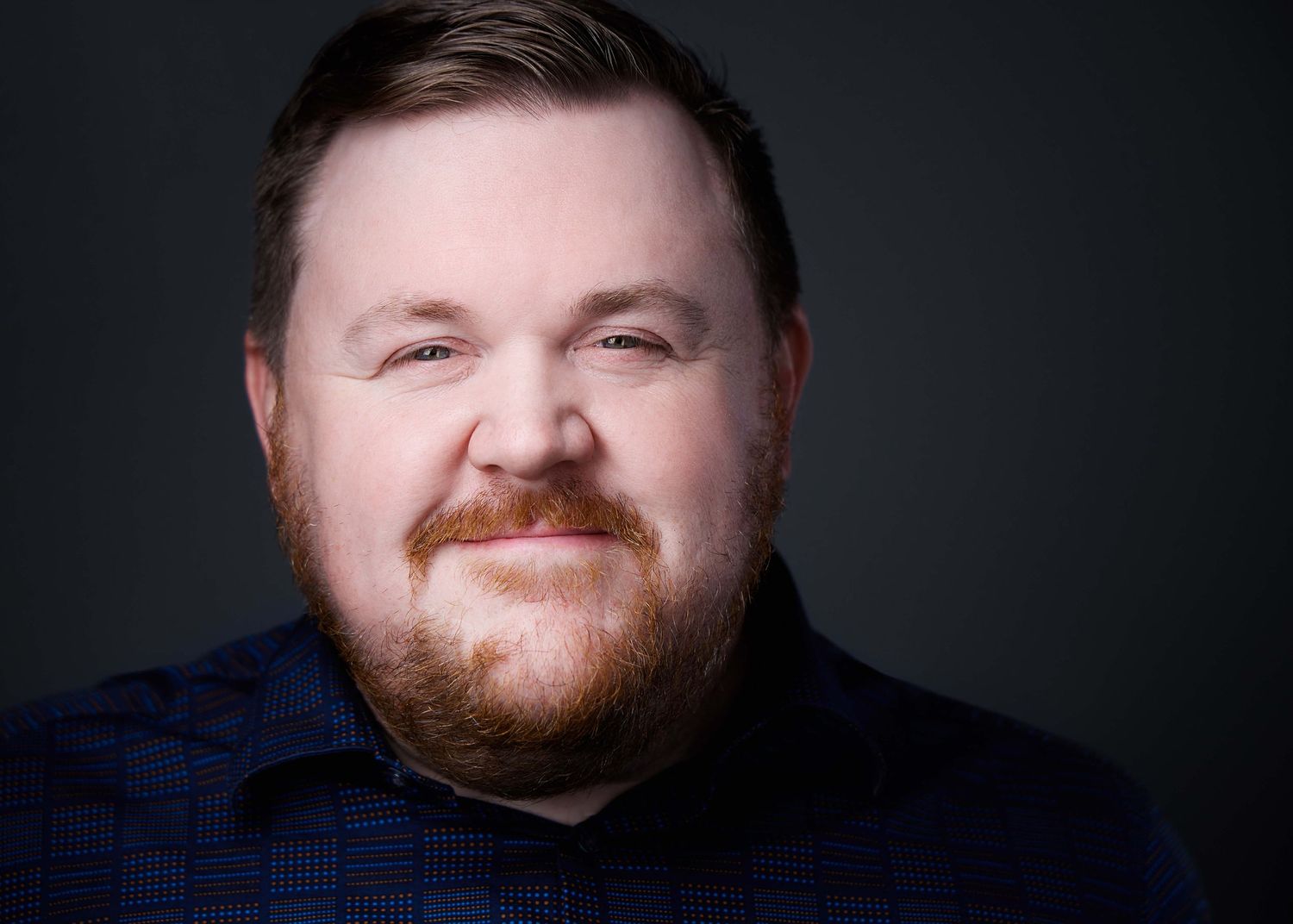 Professional portrait series showing warm expressions on dark backdrop.