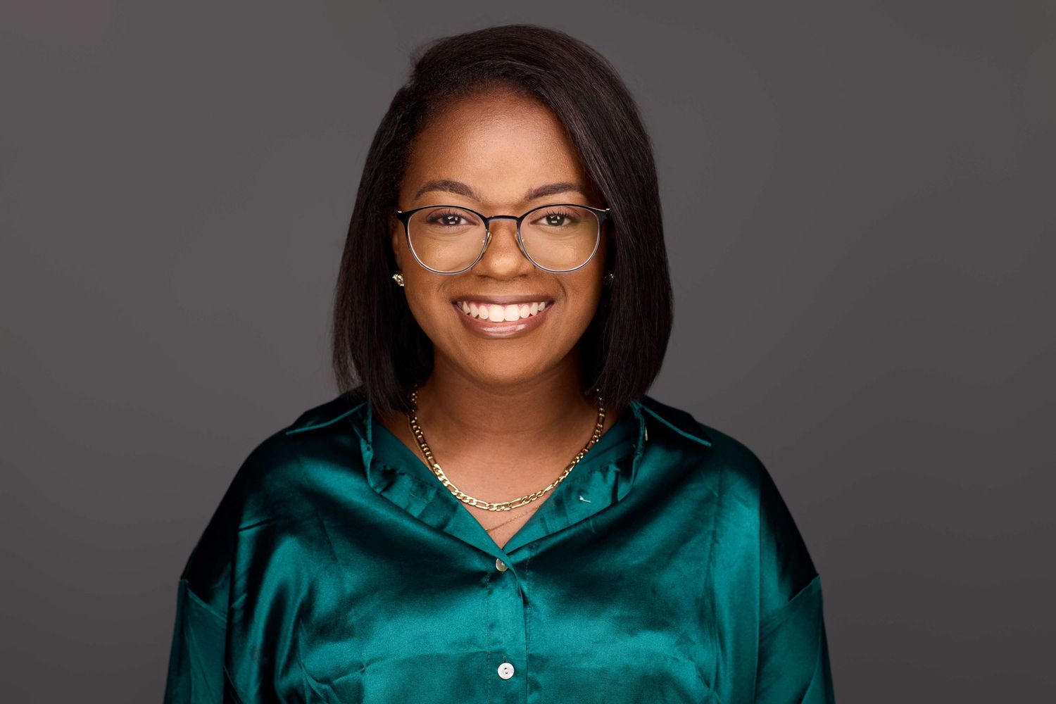 Professional portraits of staff members wearing teal colored tops against dark background.