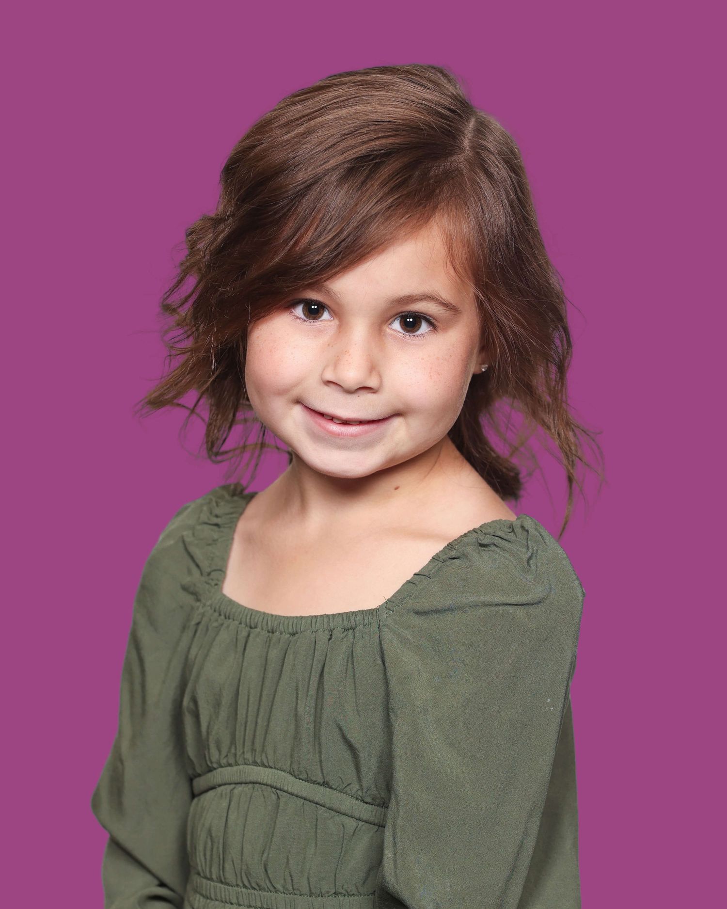 A child wearing a green peasant-style top smiles warmly against a purple background.