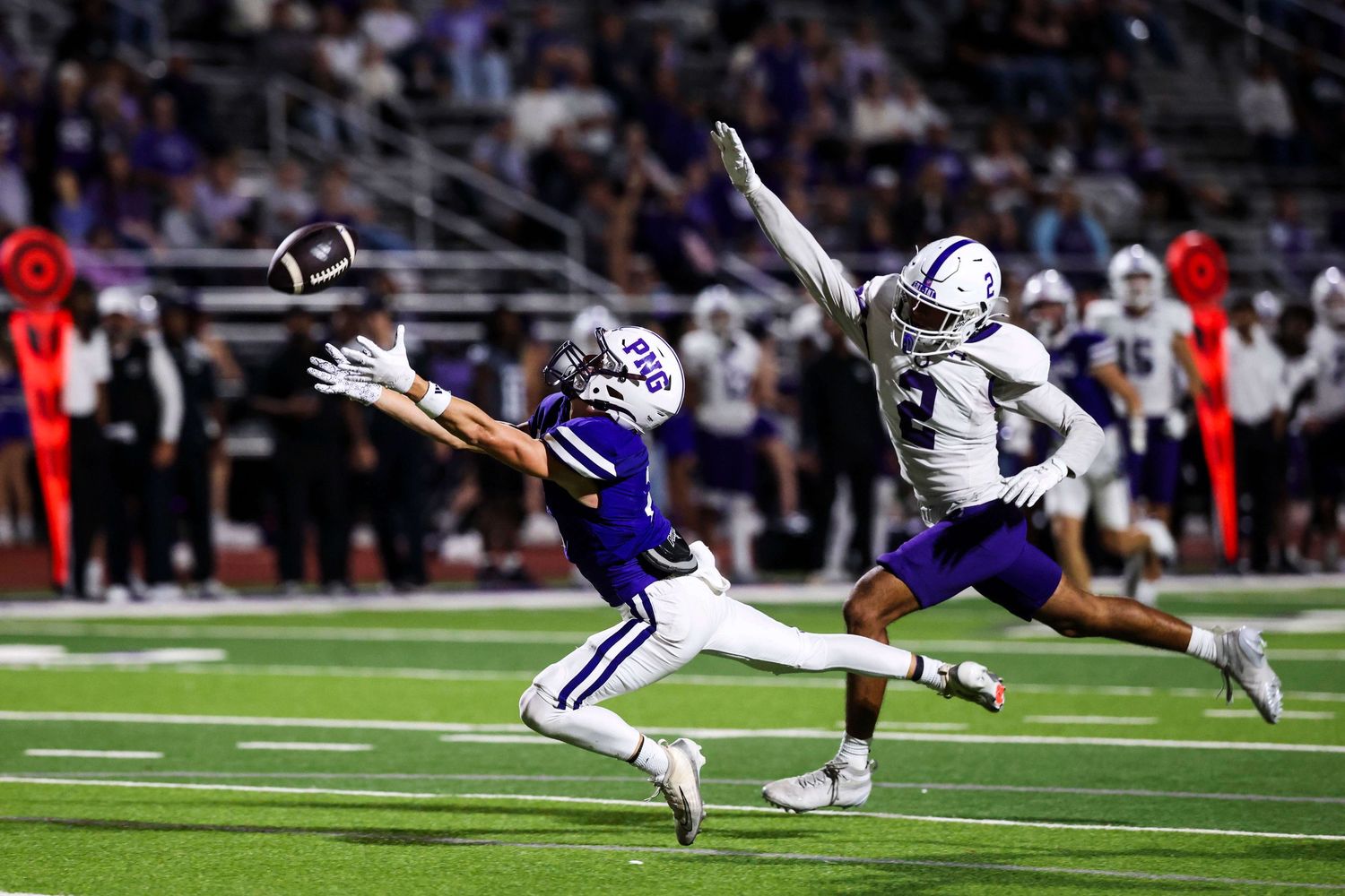 Action shot of football players making diving tackles during a night game.