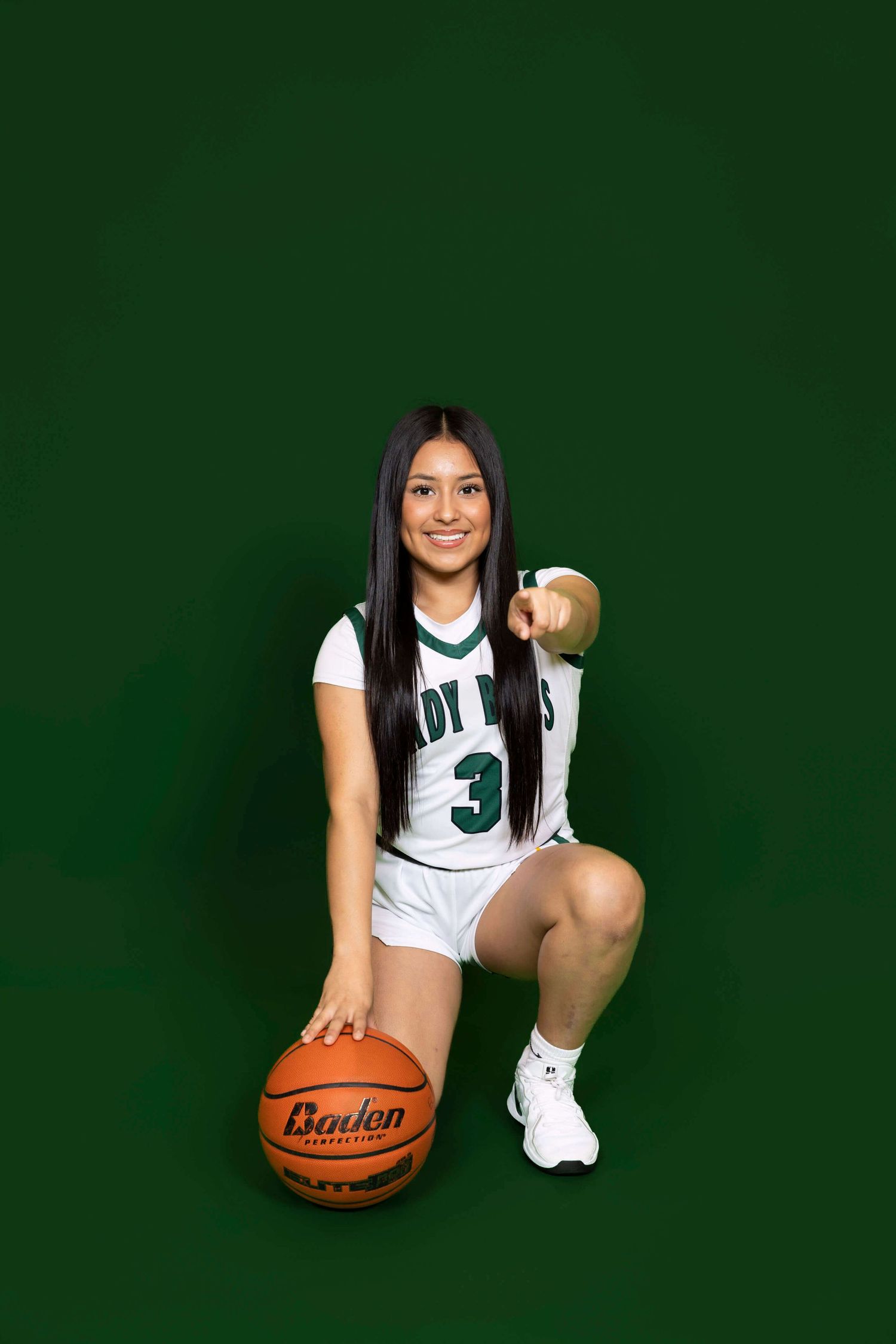 Basketball player in white jersey number 3 poses with ball against dark green backdrop.