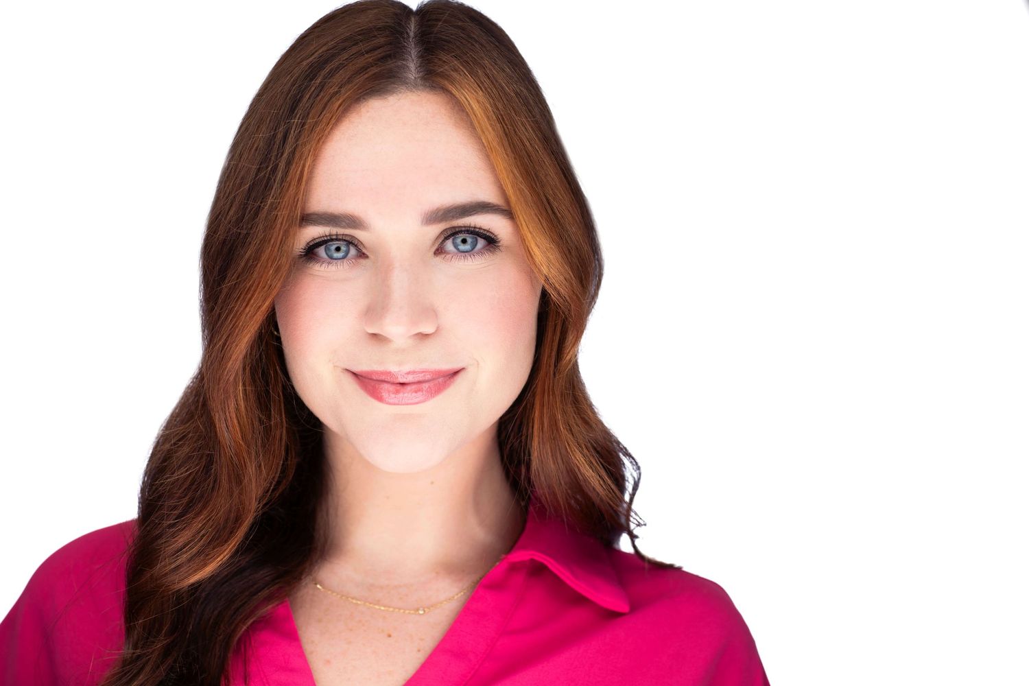 Professional portrait of person in pink top against white background.