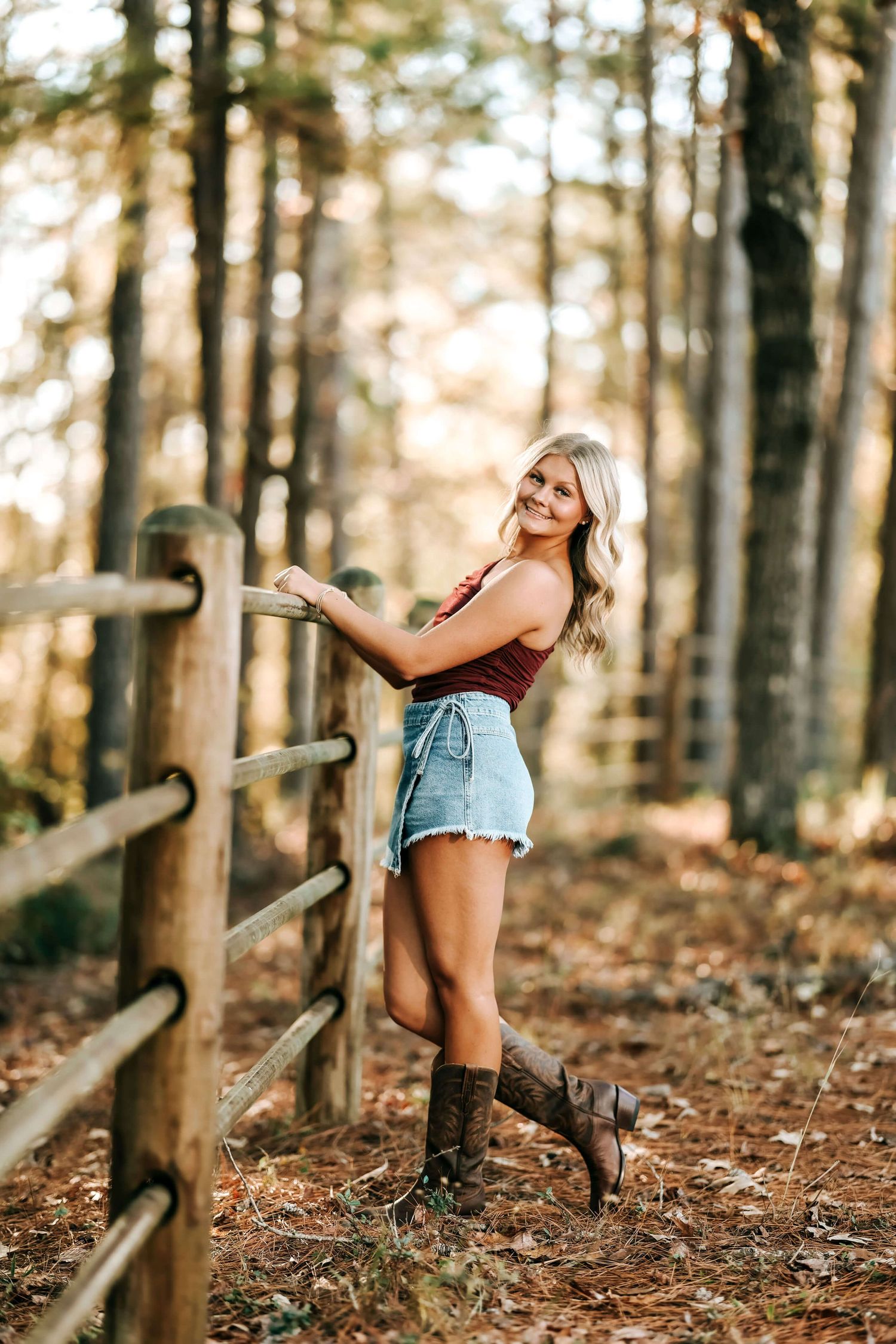 Outdoor photoshoot in forest setting with rustic wooden fence.