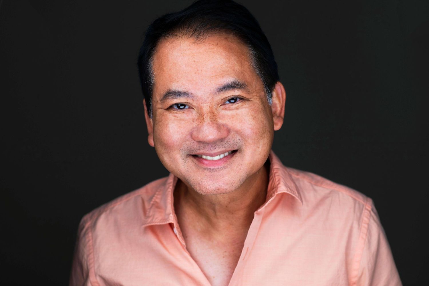 Professional portrait series of person in pink shirt against dark backdrop.