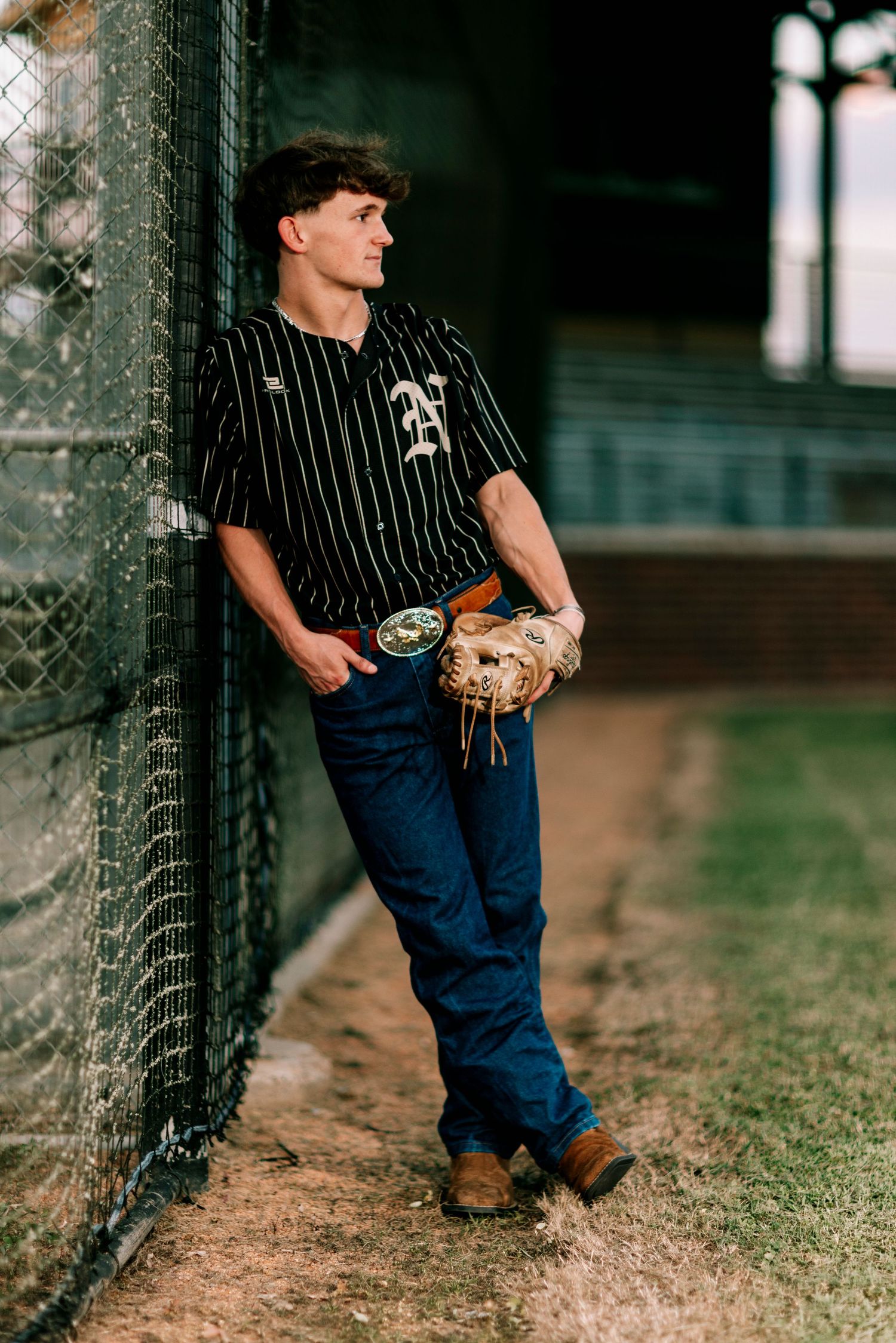 Baseball themed photo shoot featuring pinstripe uniform and chain link fence.