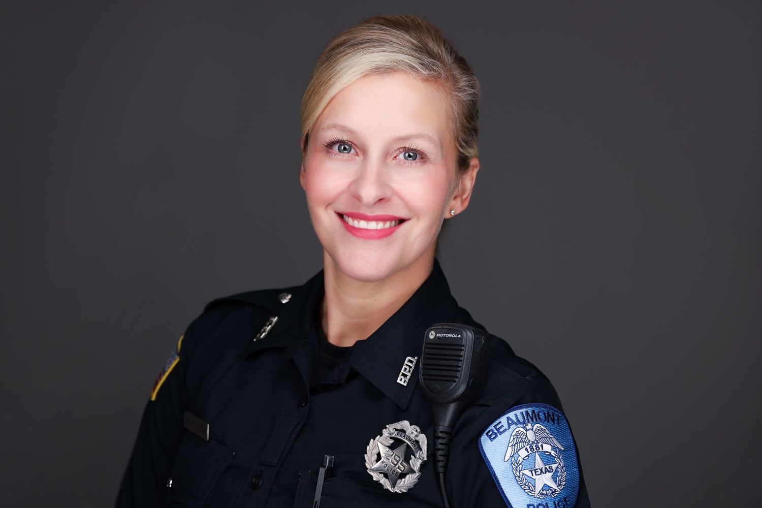 Professional portrait of person in police uniform with badge and patches.