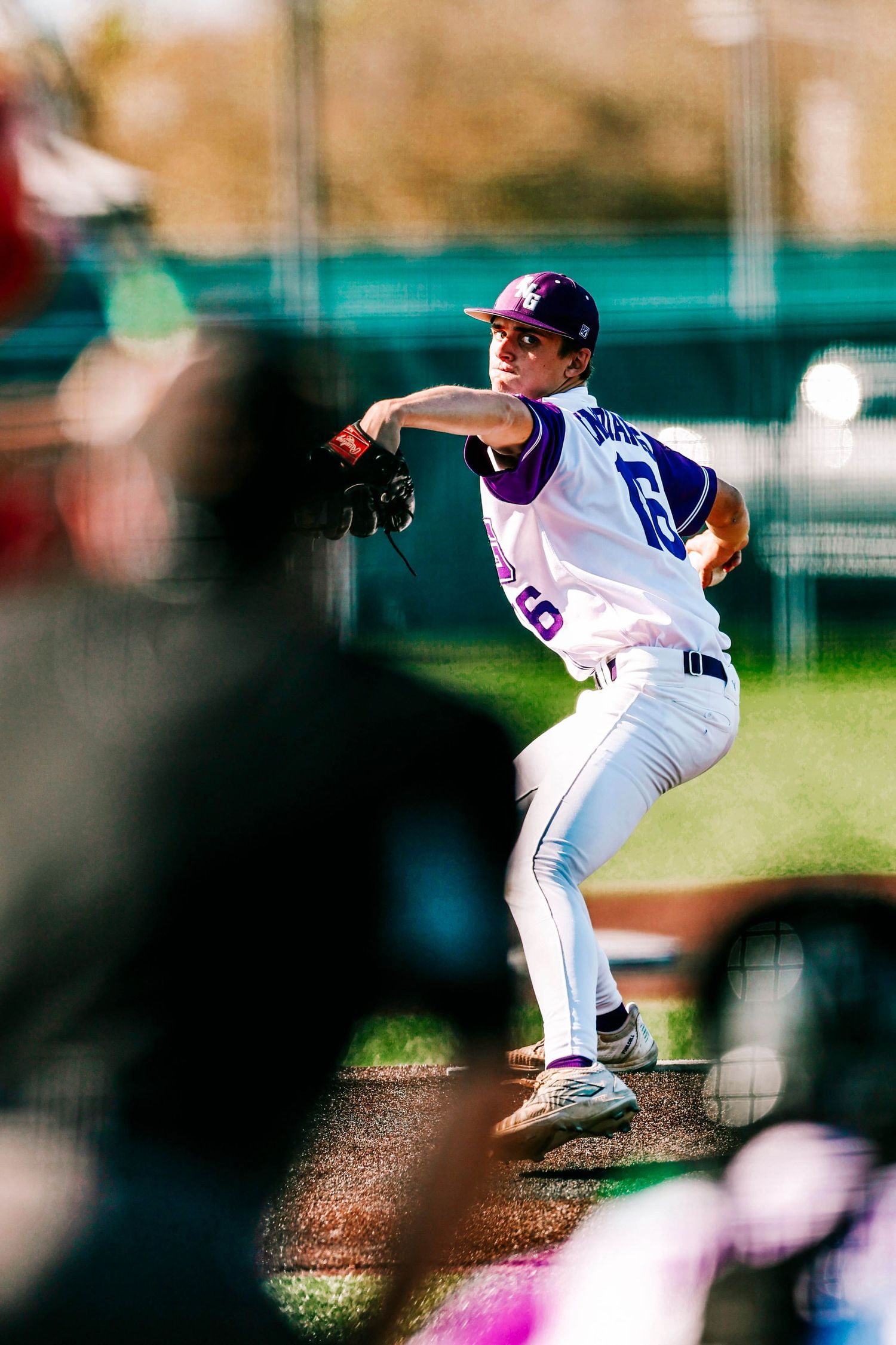 Baseball pitcher in white uniform mid-delivery on the mound during a game.