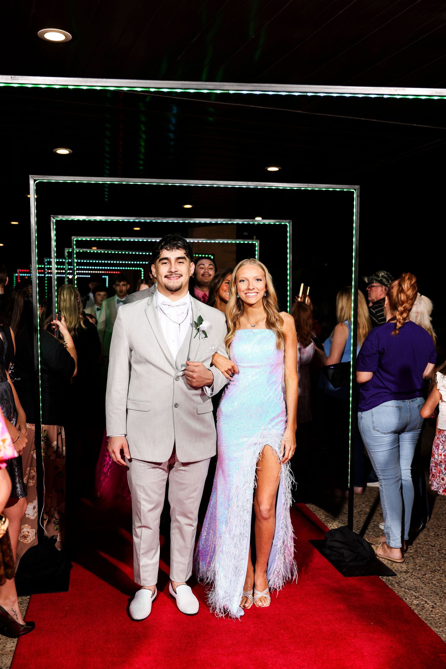 Couples pose for photos on a red carpet at a formal event in elegant evening attire.