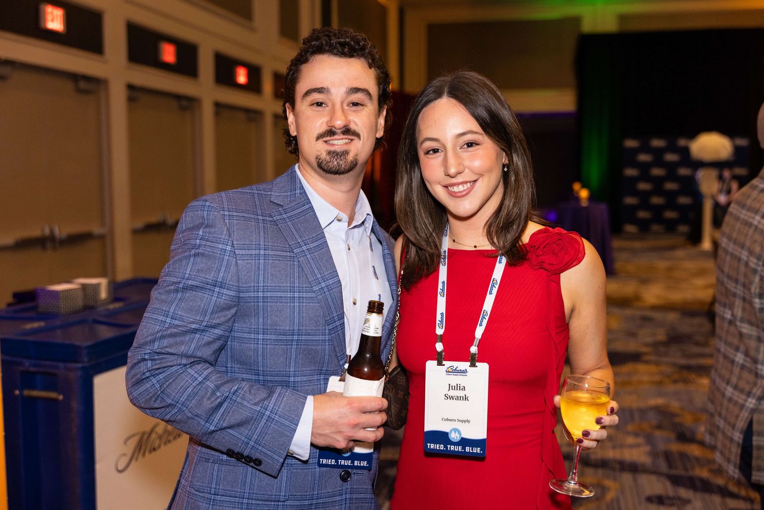 Business professionals networking and socializing at an indoor corporate event with drinks.
