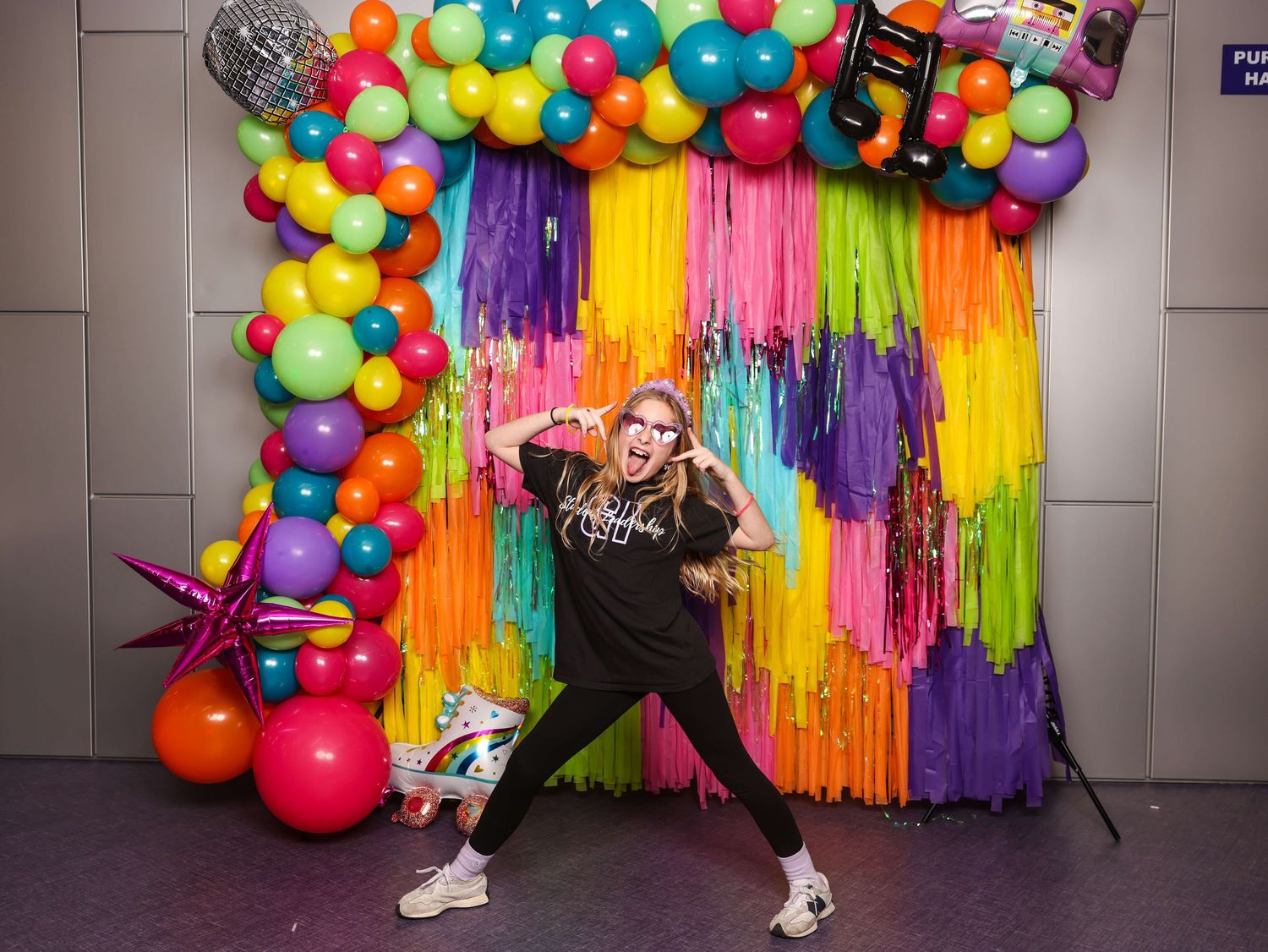 Colorful balloon arch installation with vibrant streamers in rainbow colors creates a festive party backdrop.