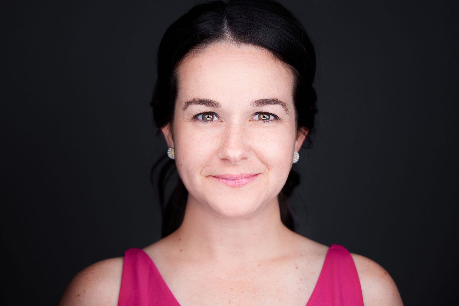 Studio portraits with bright pink top against dark background.
