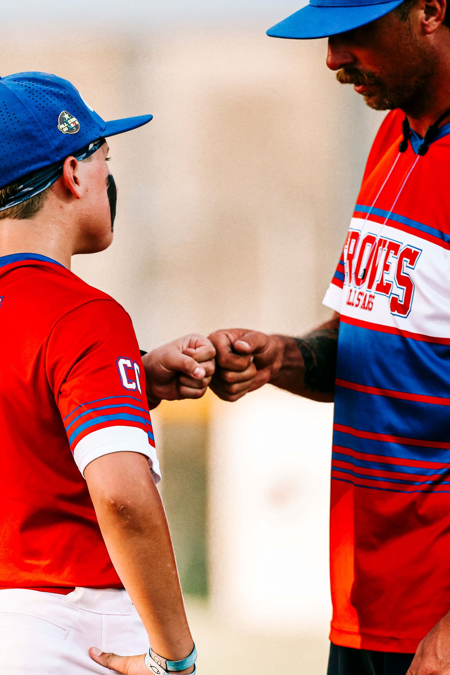 Baseball coach and young player share fist bump during game.