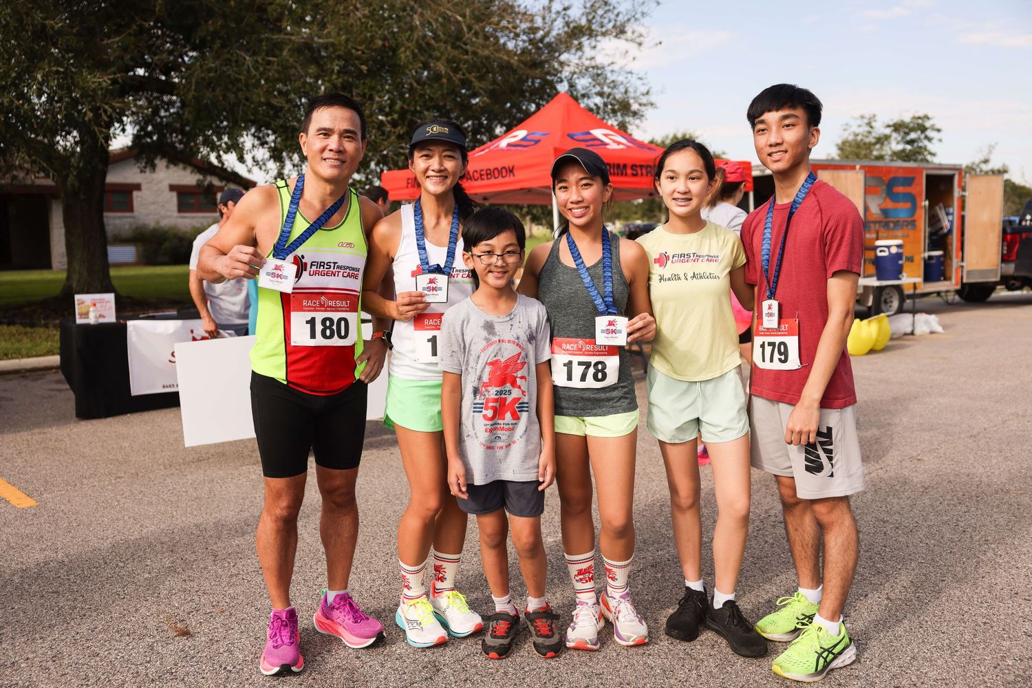 Group of runners in colorful athletic gear posing together at a community race event.