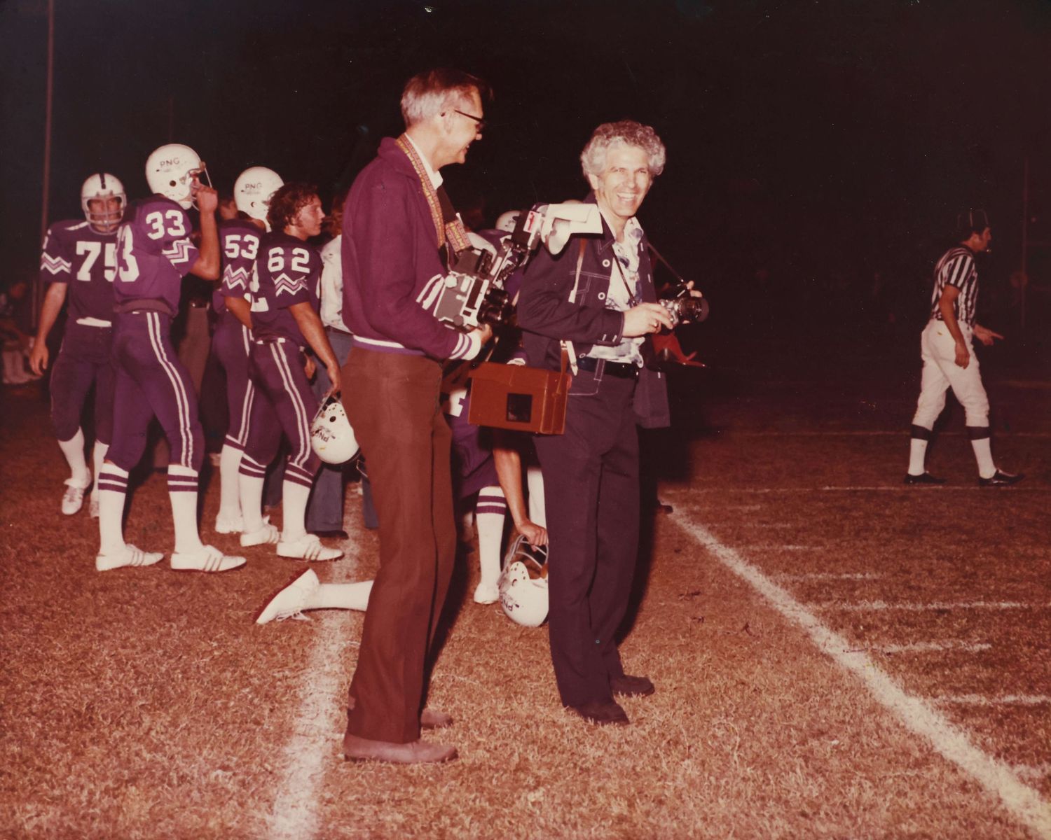 Vintage sepia photograph of football players and coaches on sideline.