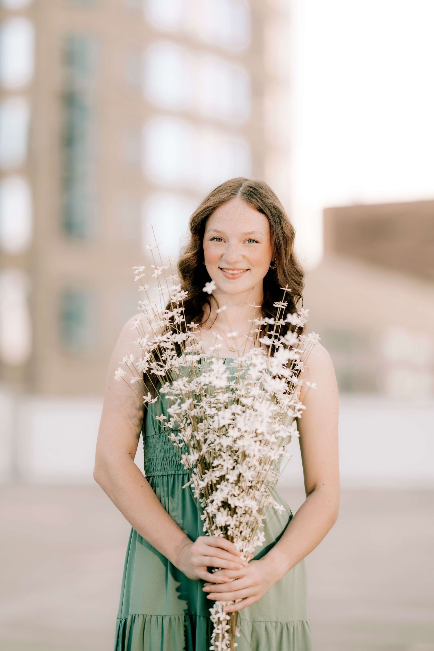 Portrait session featuring a green dress and delicate white baby's breath flowers.