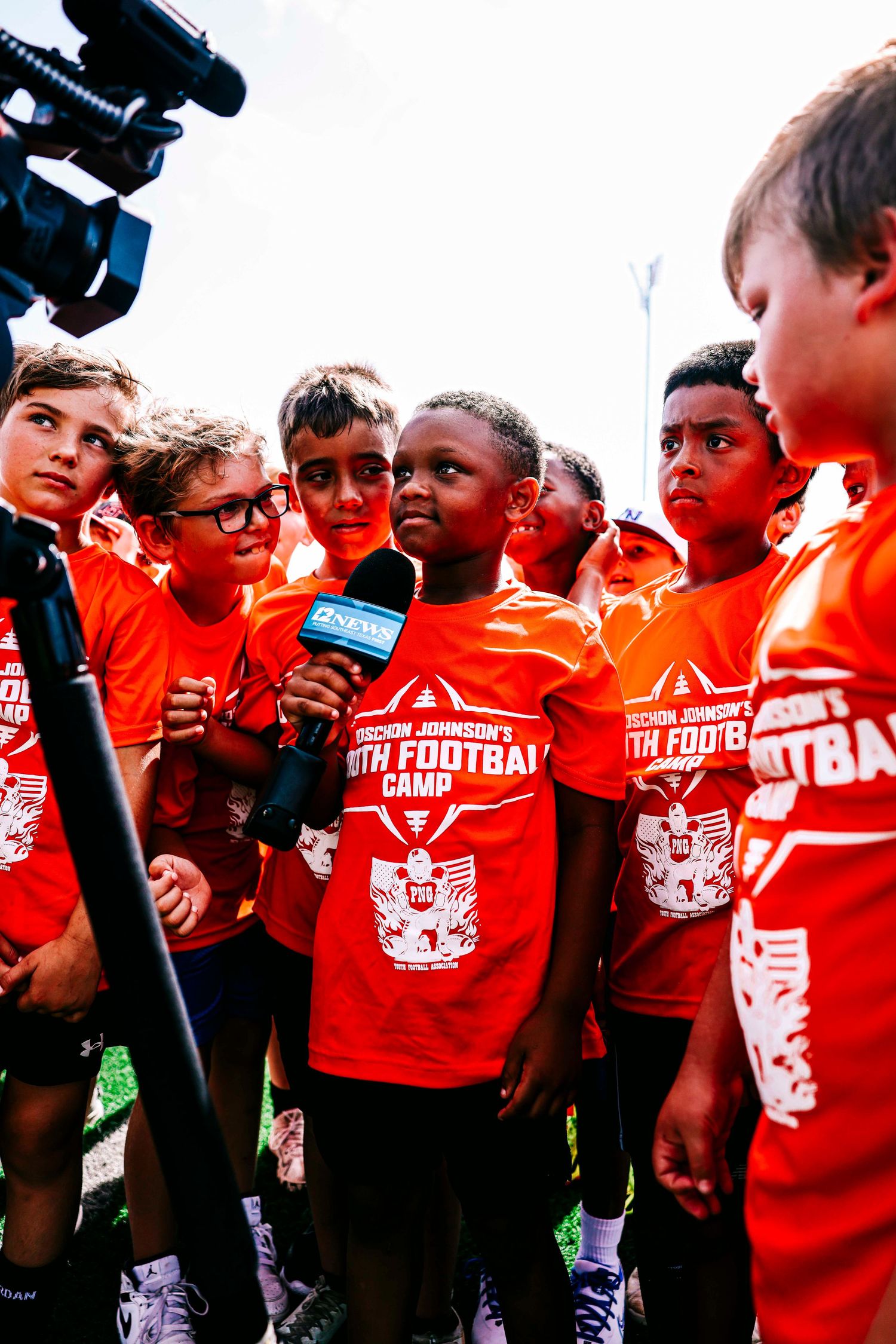 Group of young athletes in red jerseys huddle together at sports event.