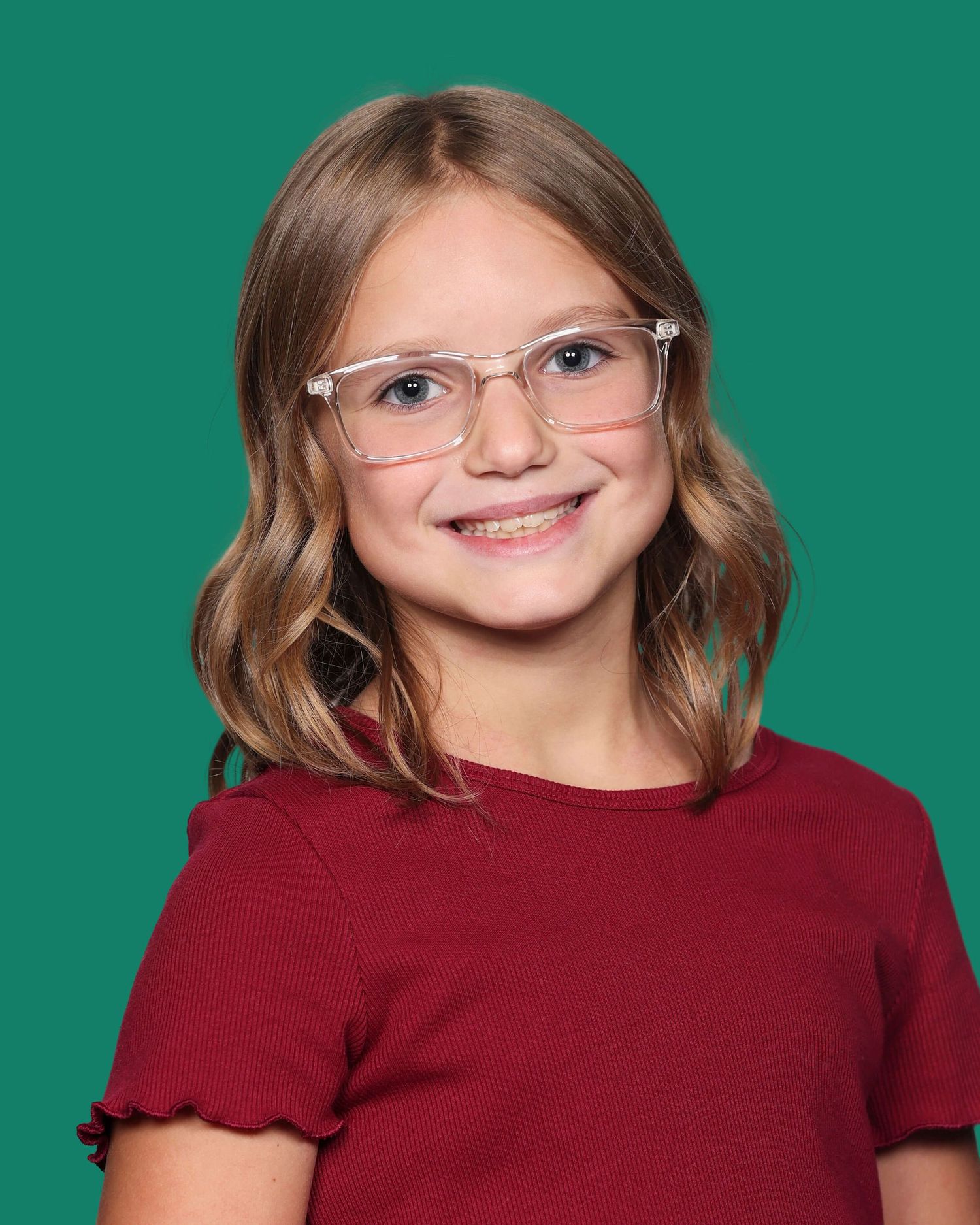 A young person in a red top smiles warmly against a vibrant teal background.