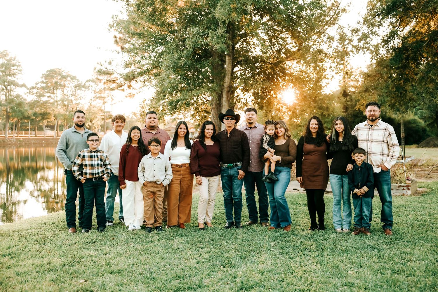 Extended family group photo with multiple generations lined up outdoors at sunset.
