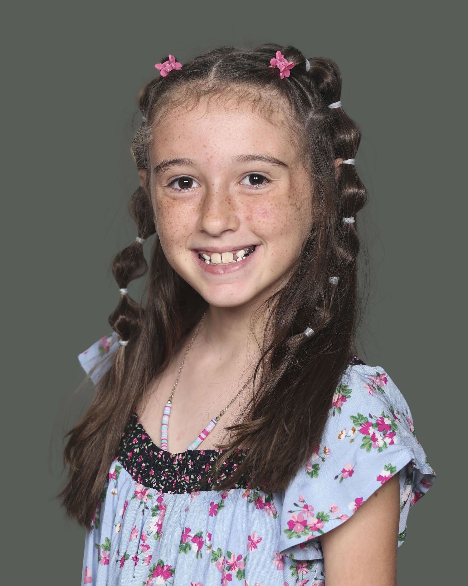 Young child wearing a light blue floral dress with small pink flowers in their hair.