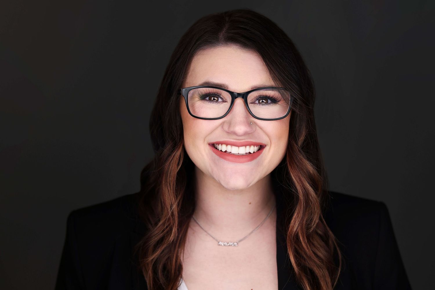 Professional headshot portrait with dark background and warm smile.