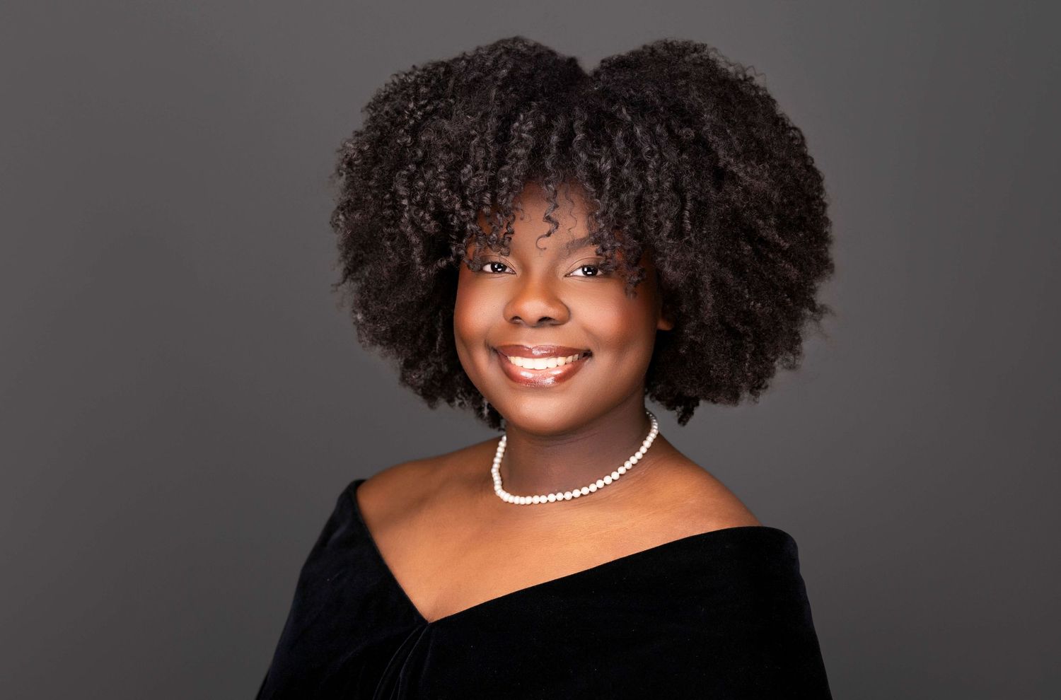A series of six headshots showing different poses and expressions with natural curly hair and a pearl necklace.