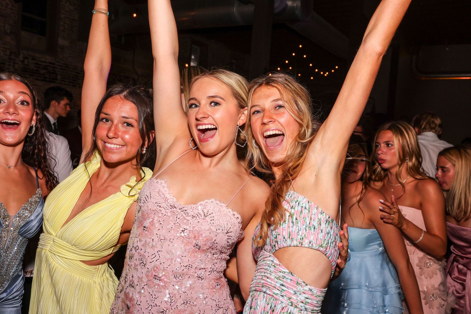 A group of people dancing and celebrating at a lively party with their arms raised in excitement.
