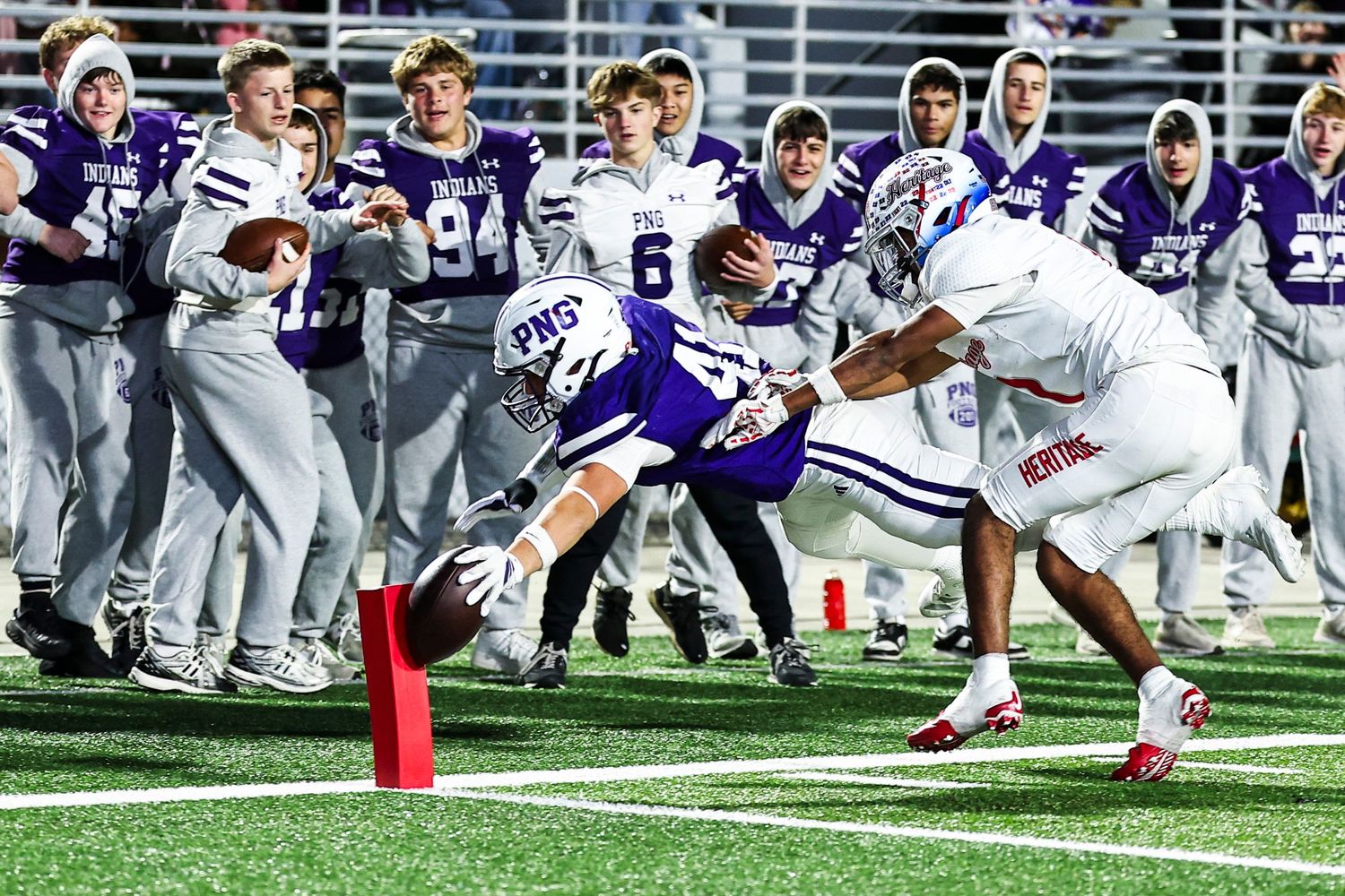 Football team in purple and white uniforms performs synchronized moves on the field.