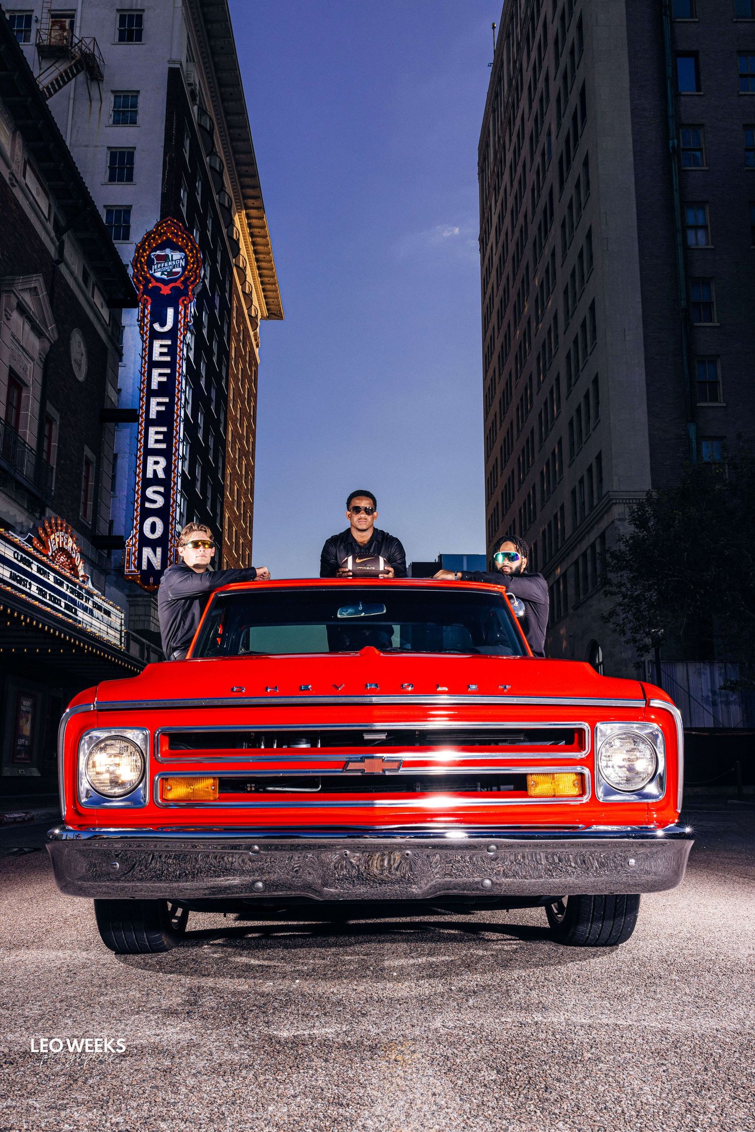 Front view series of classic red Chevrolet car against urban backdrop with neon signs.