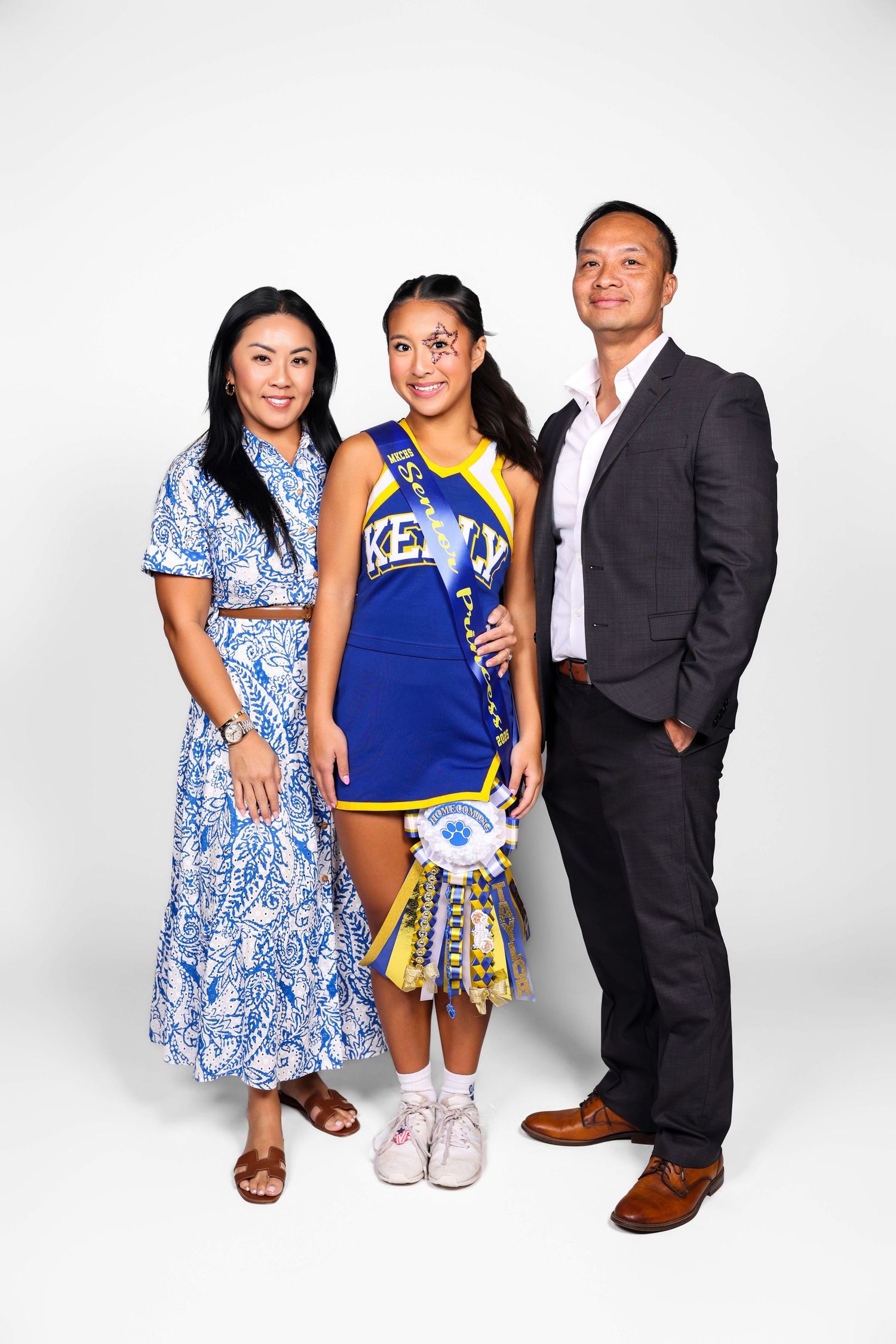 A family poses together in coordinated blue and white outfits against a white studio backdrop.