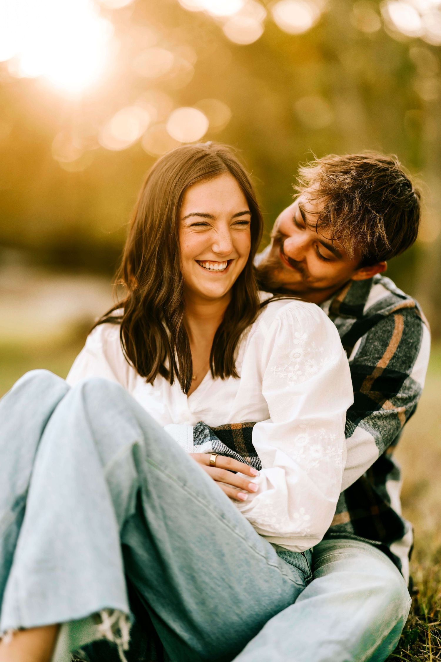Two people share a tender moment wrapped in a cozy blanket outdoors.