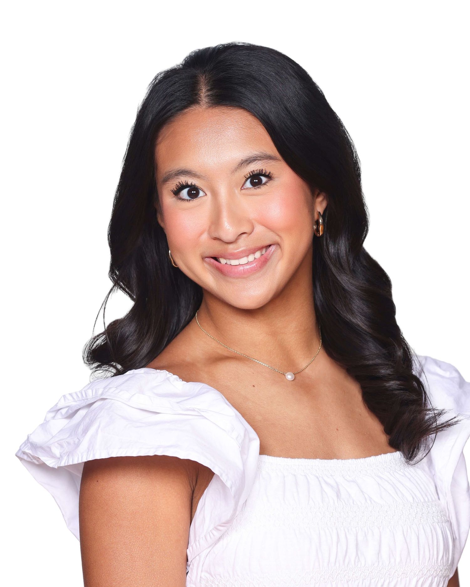 Woman in white off-shoulder top smiling at camera against white background.