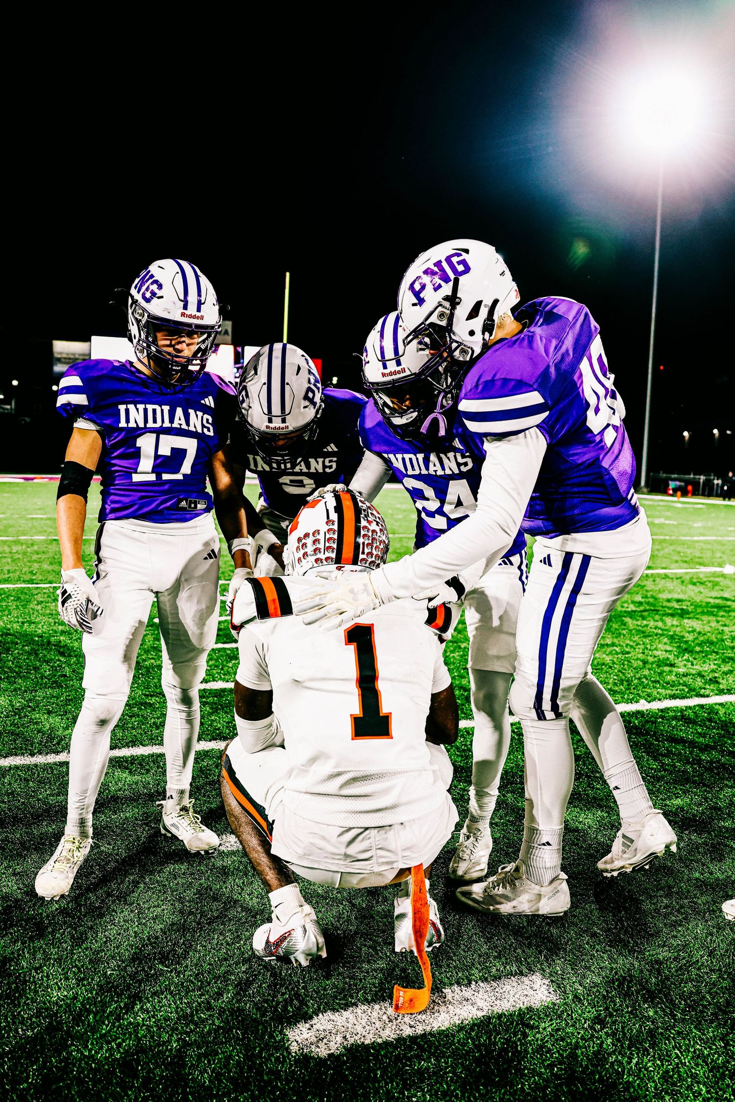 Football players from opposing teams gather on field after game.